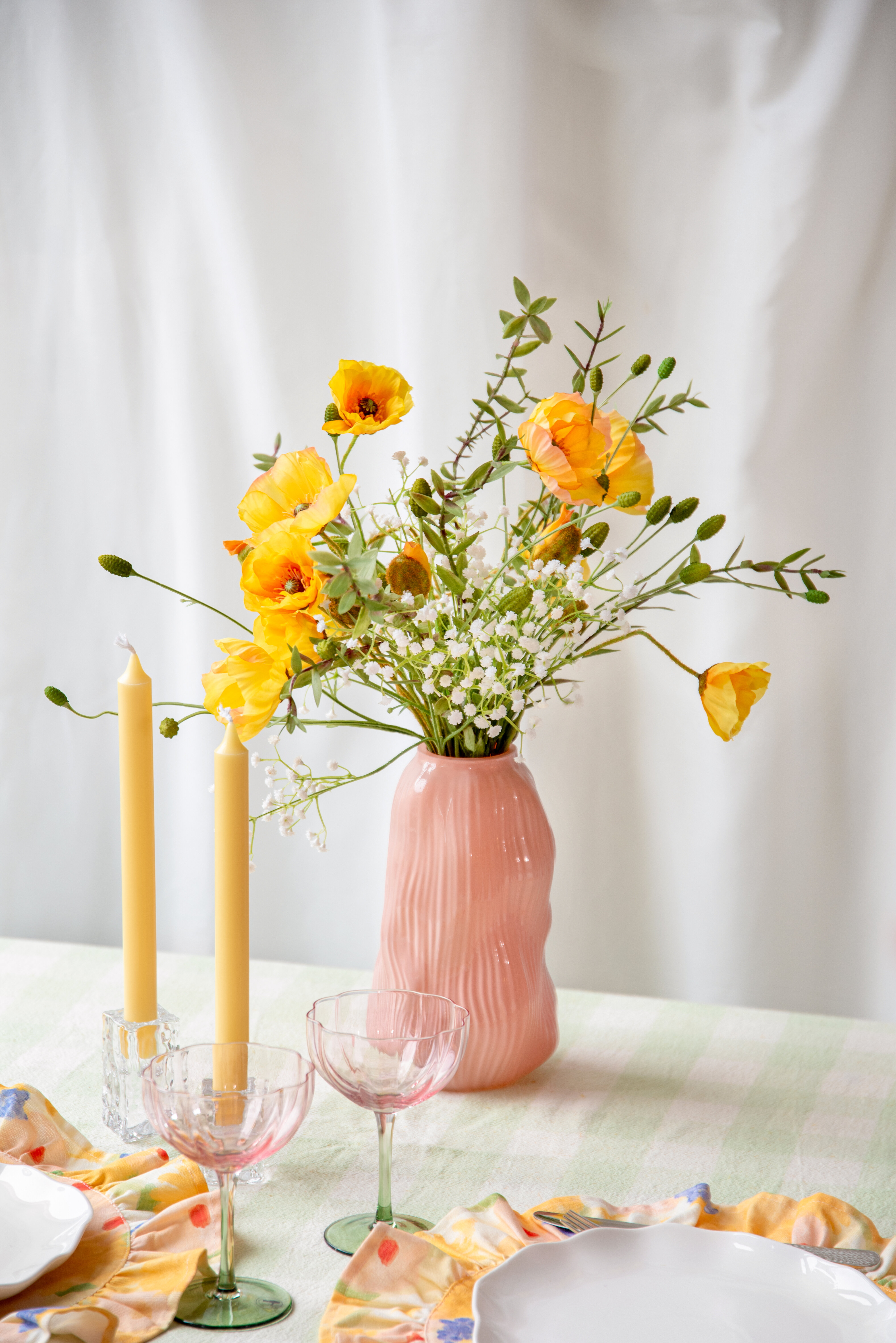 Rosa vas med blommor i placerad på ett dukat bord.