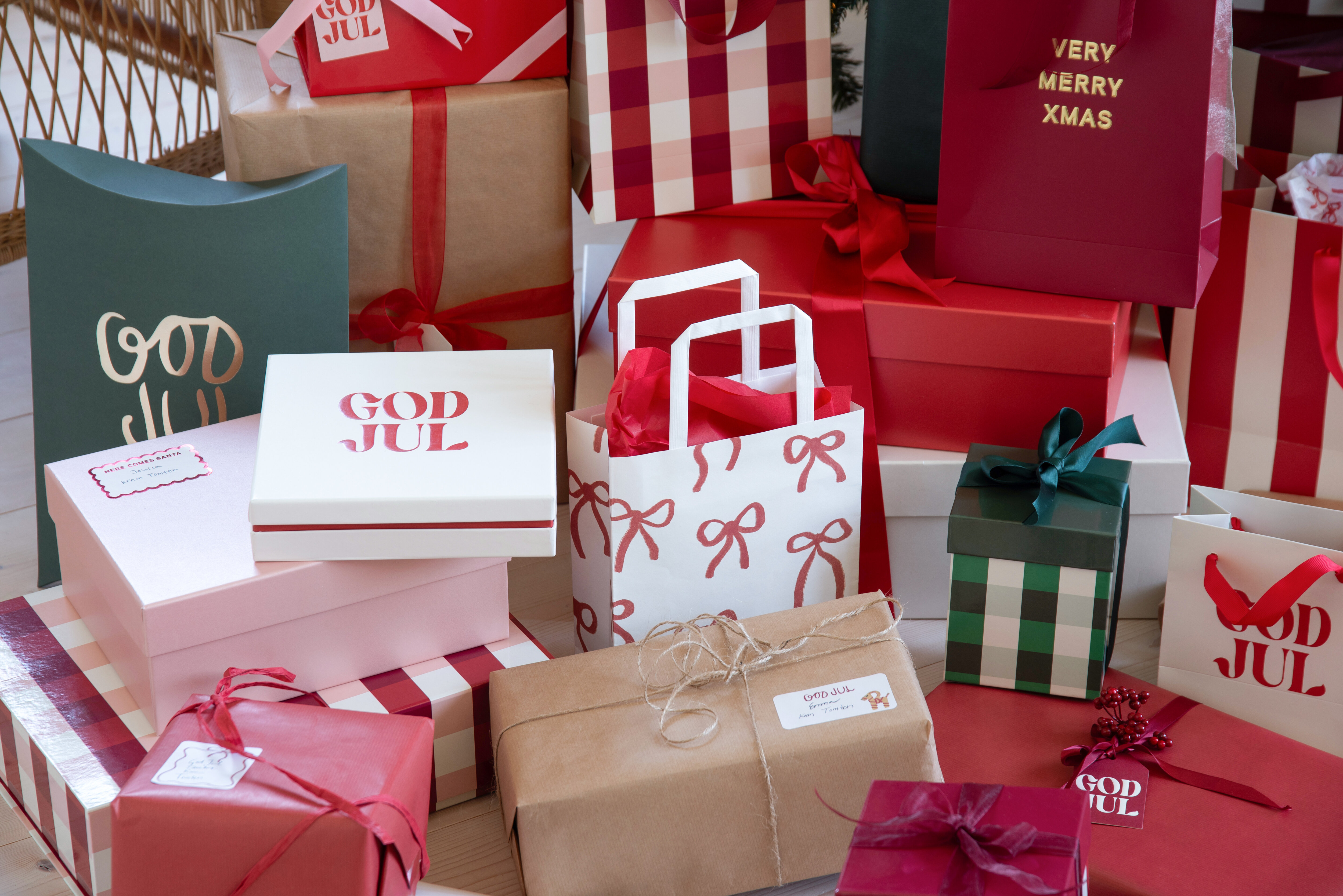 Julklappar och presentpåsar i rött, vitt och grönt med julmotiv och rosetter.
