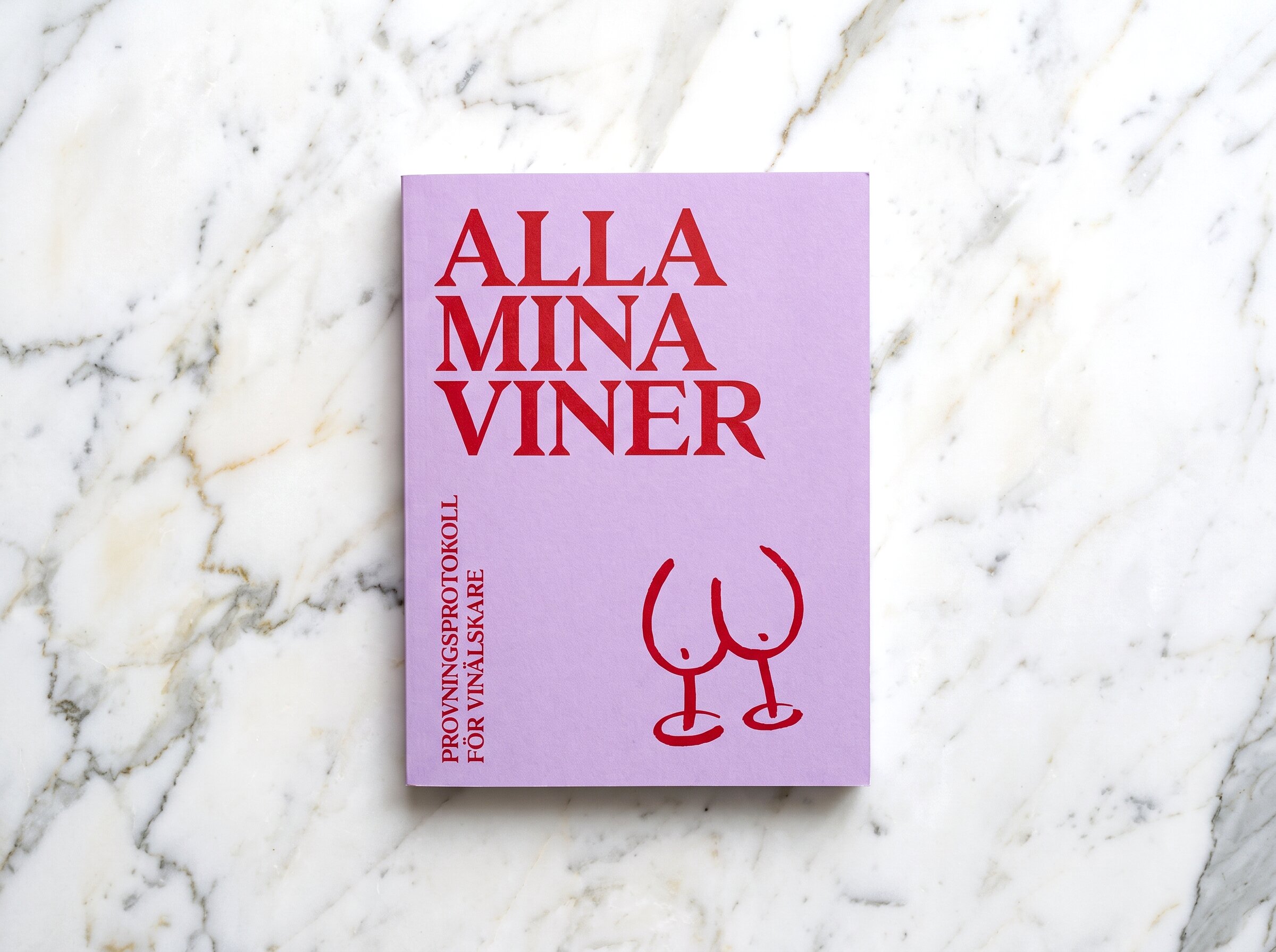 Lila och vinröd bok om vin mot marmorunderlag.