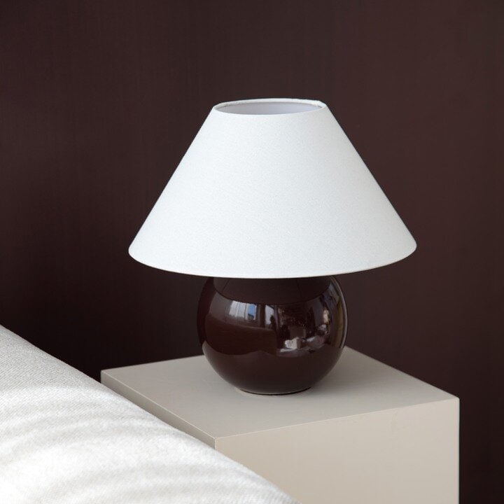 Bordslampa på en piedestal mot mörk bakgrund.