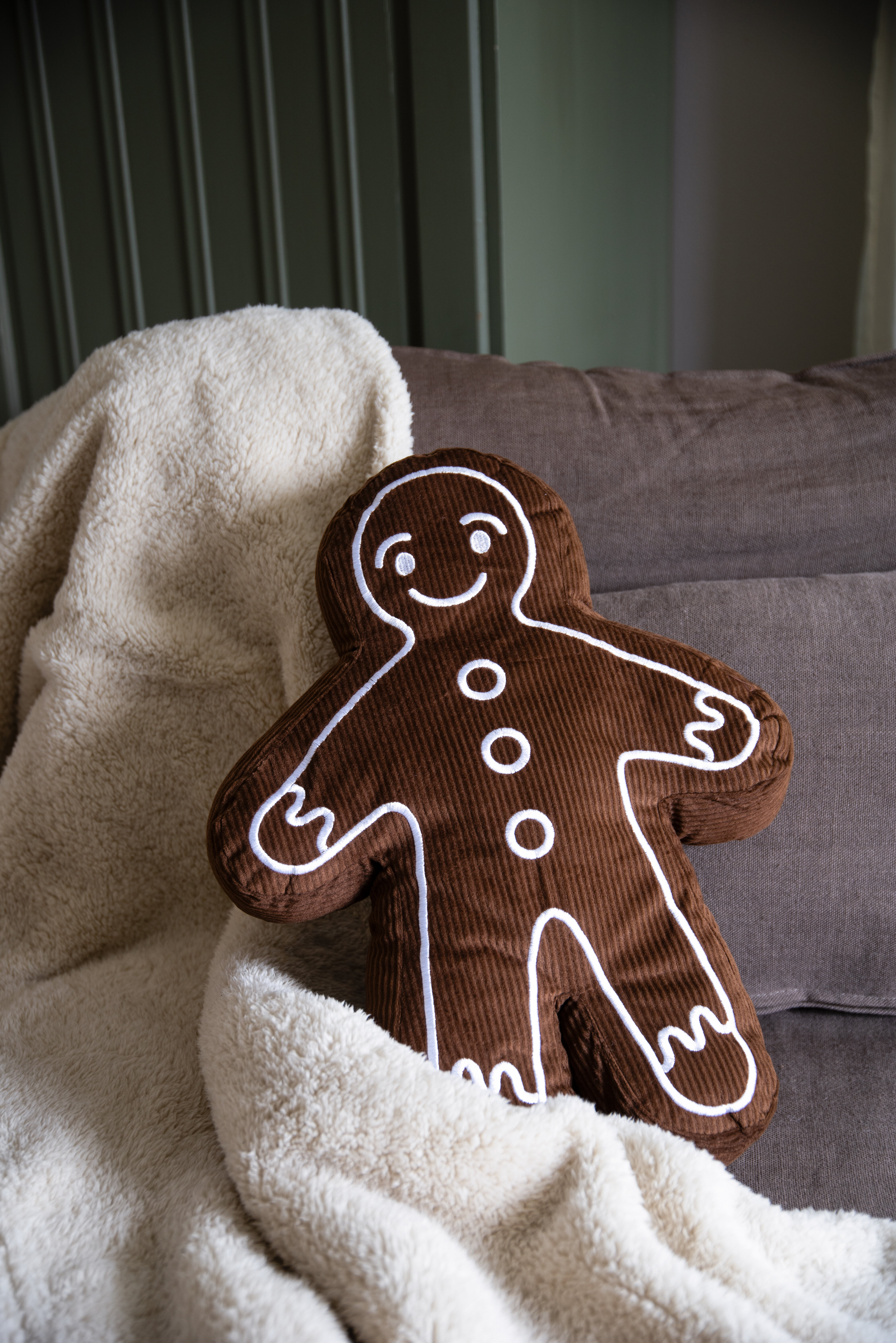 Brun figurkudde formad som en pepparkaksgubbe invirad i ljus filt.