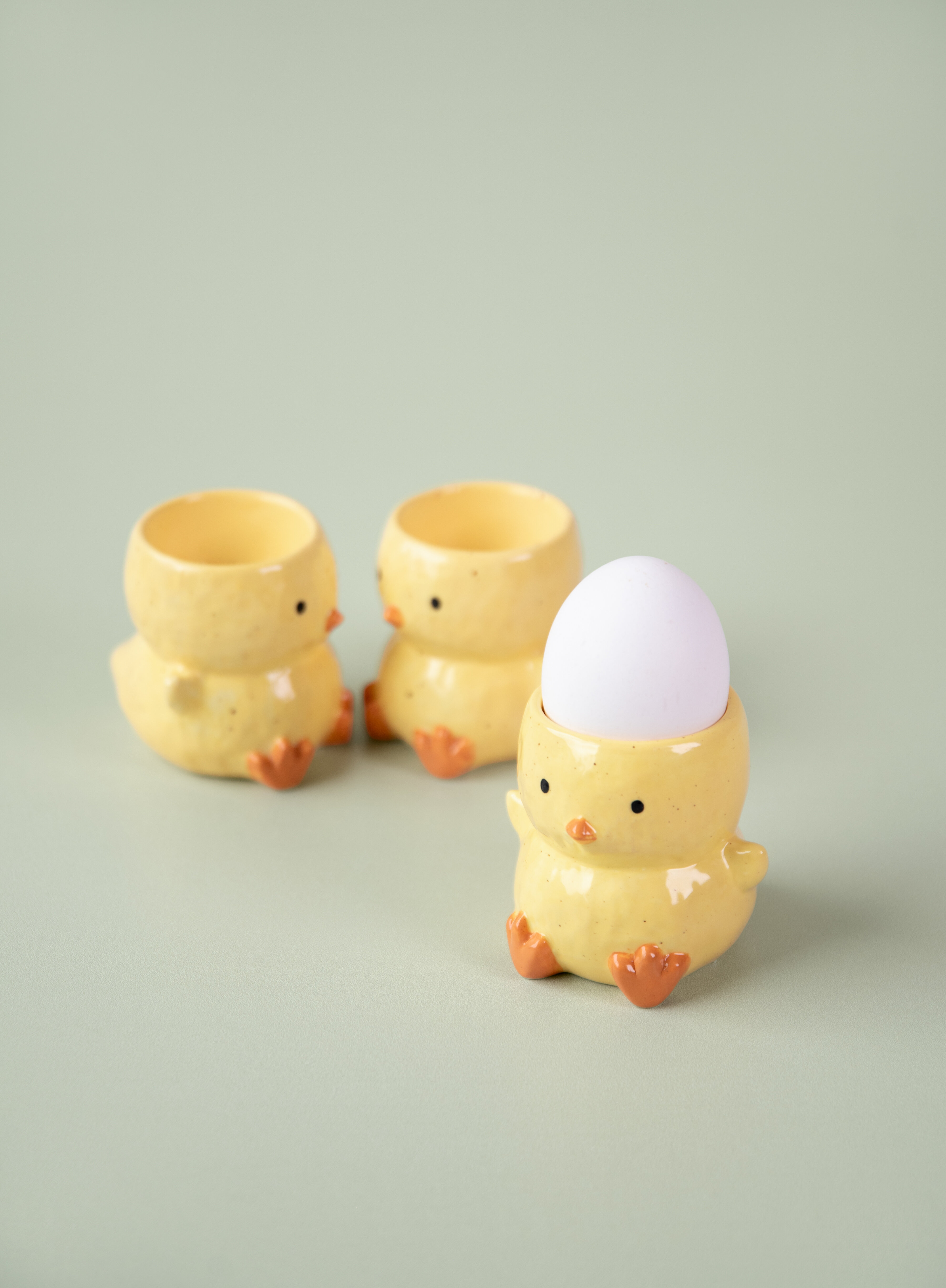 Äggkoppar som ser ut som en kyckling mot ljusgrön bakgrund.