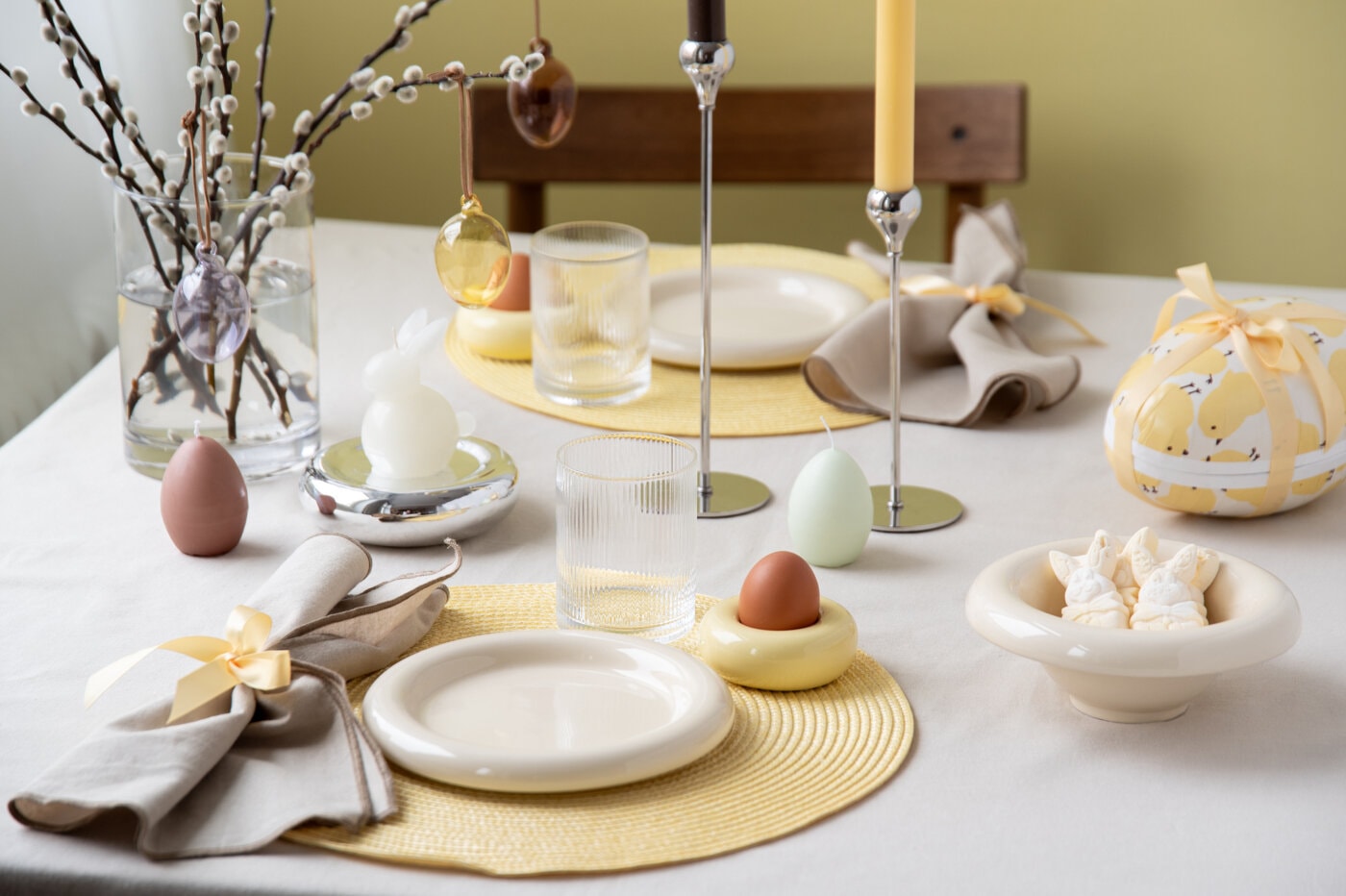Påskbord dukat i ljusa vårfärger med porslin, glas och äggdekorationer