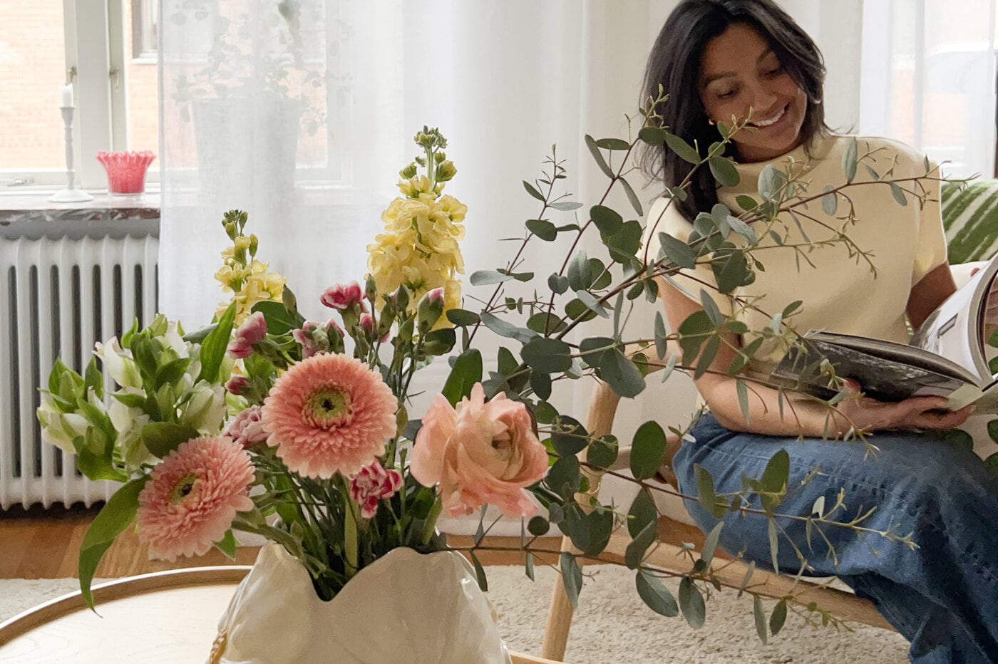 Rosa vas med blommor och färgade ljuslyktor på bord.