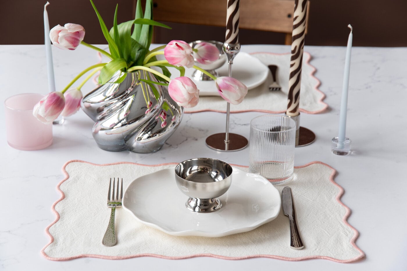 Dukat bord med tallrikar, ljus och silvrig vas.