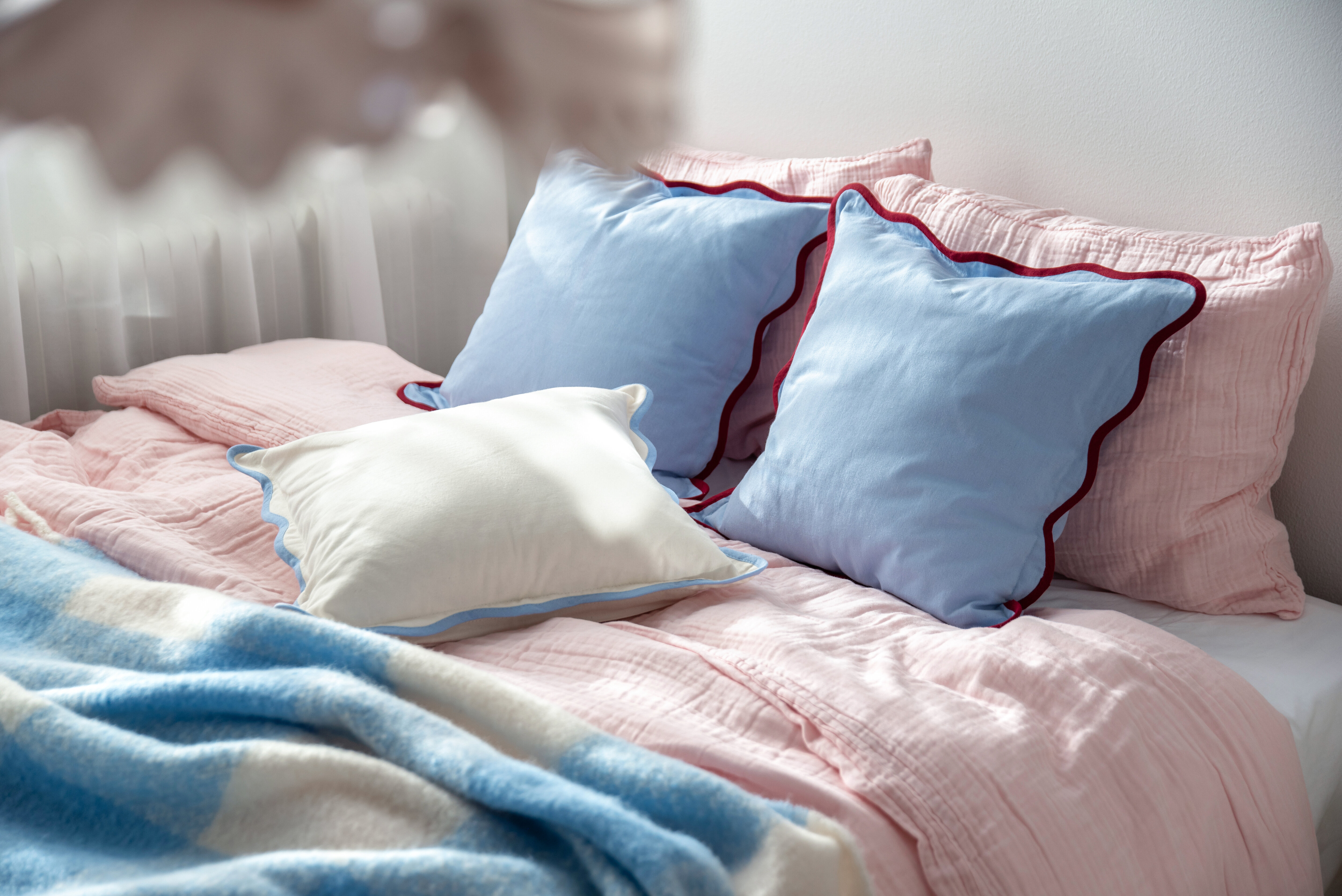 Ljusblå kuddfodral i rosa bäddad säng.