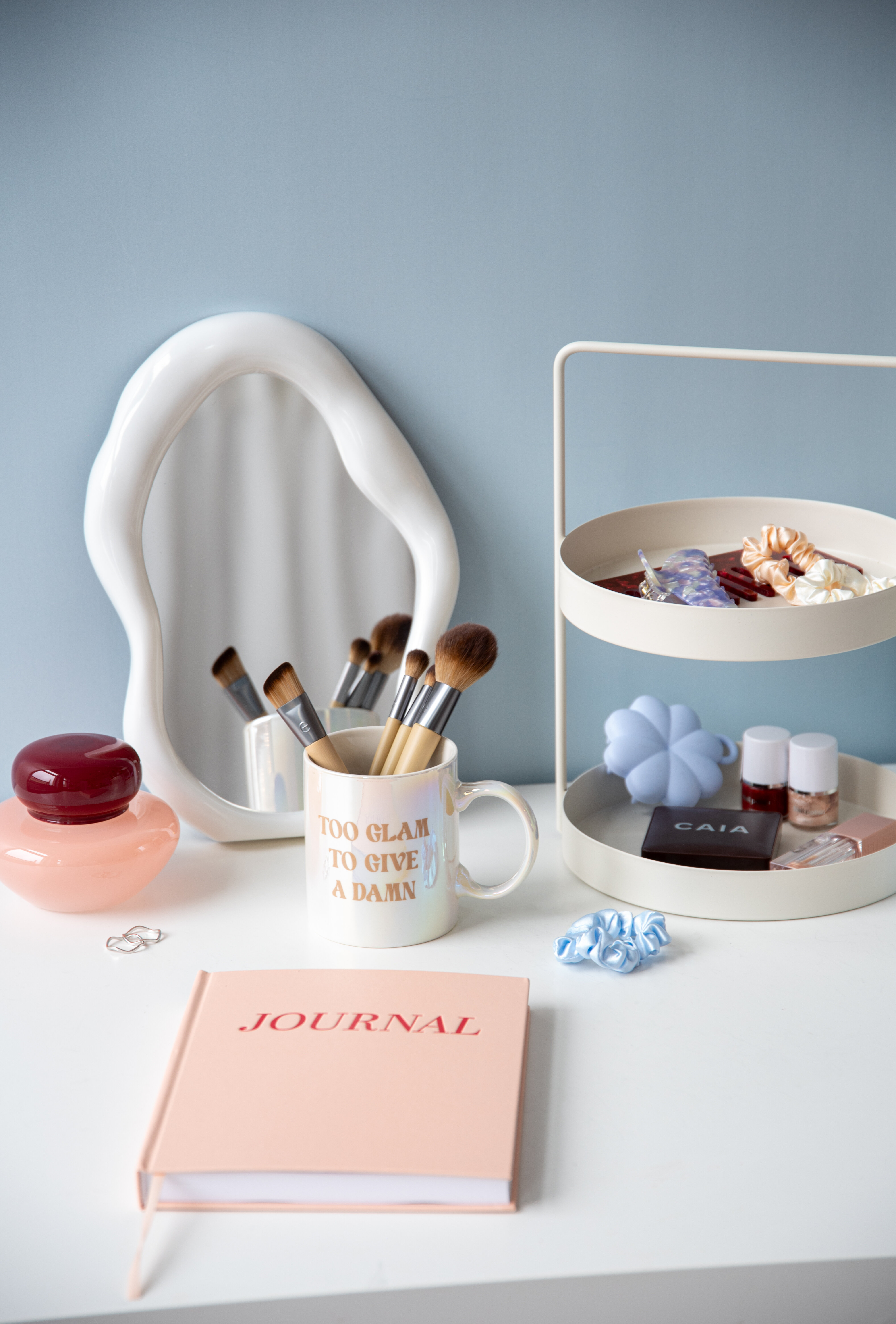 Sminkbord med spegel, sminkborstar och förvaring.