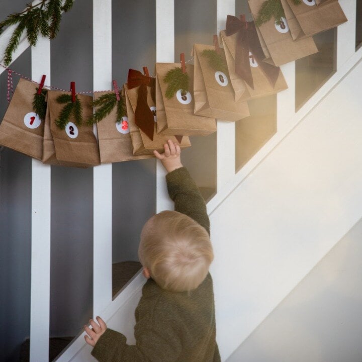 Adventskalender med små bruna påsar upphängda vid en trappa.