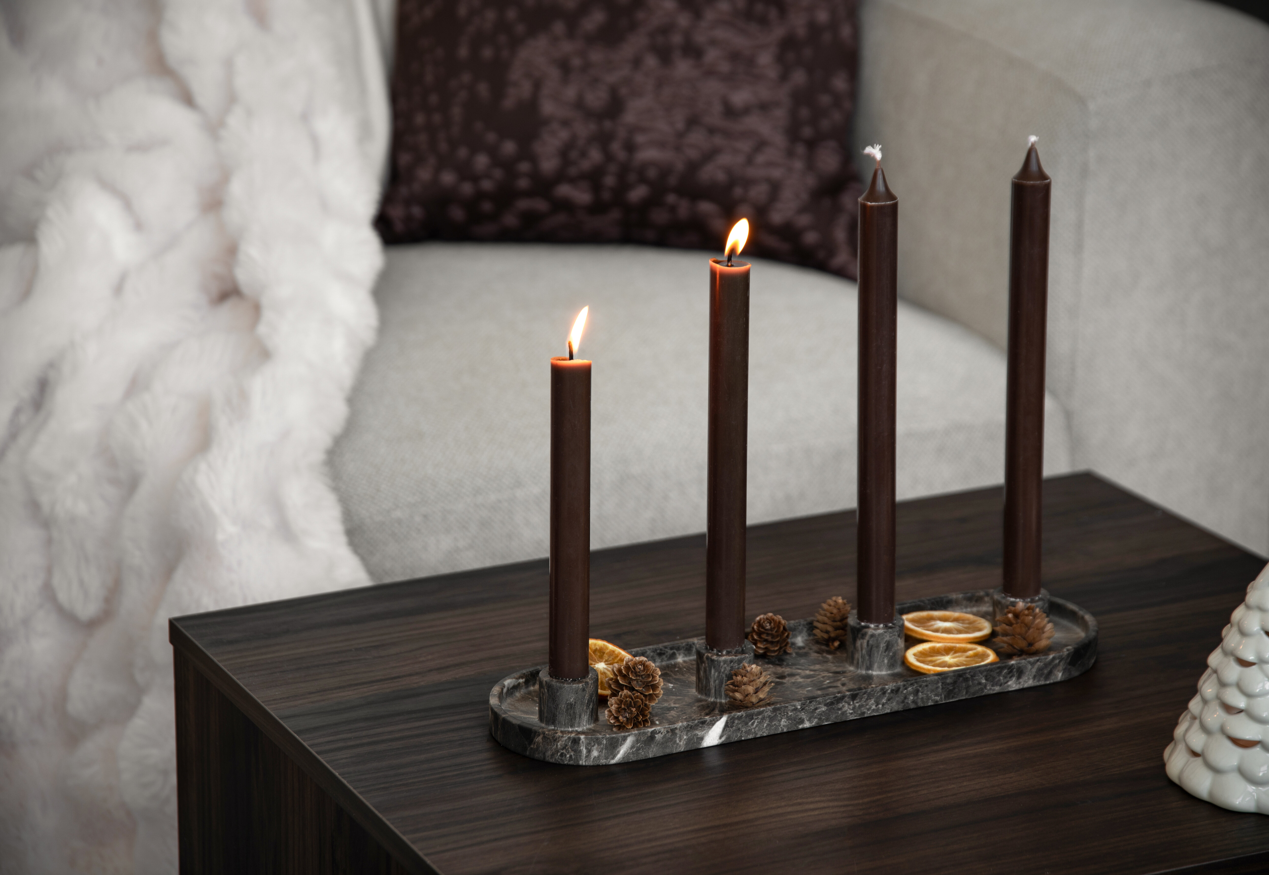 Adventsljusstake med fyra mörkbruna kronljus, kottar och torkade apelsinskivor.