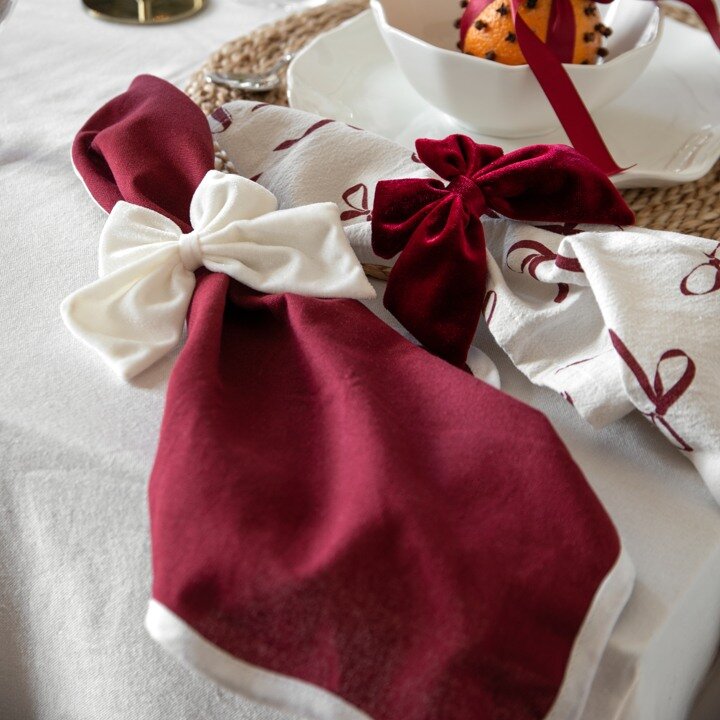 Juldukning med vinröda och vita servetter dekorerade med sammetsrosetter.