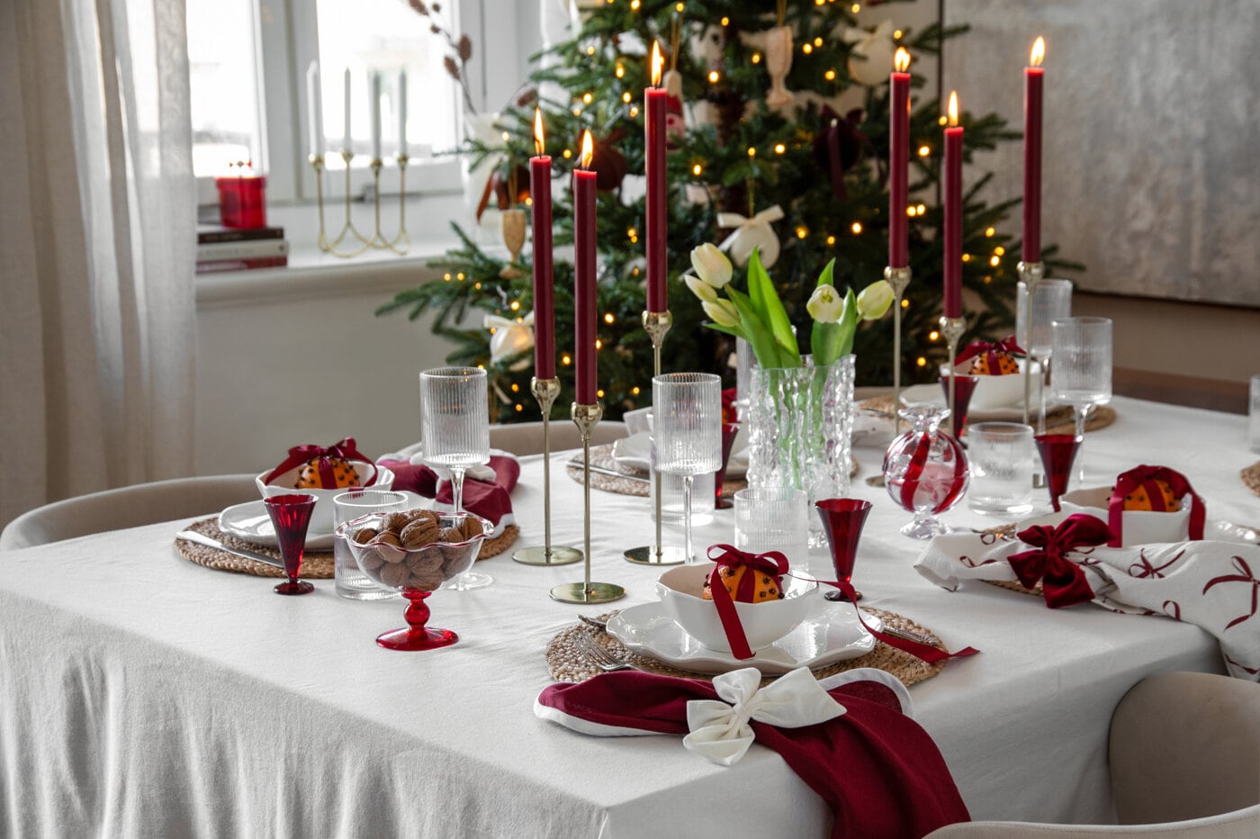 Juldukning i rött och vitt med tända ljus och julgran.