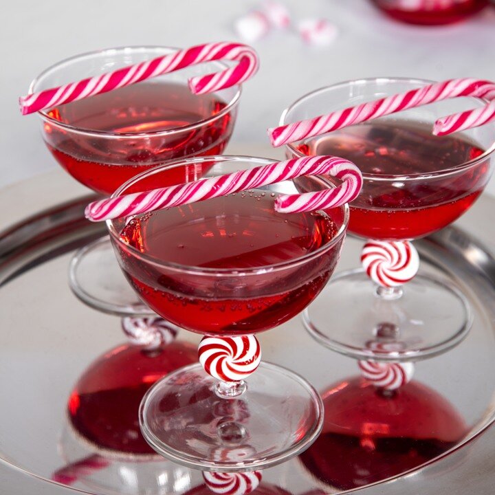 Cocktailglas med röd dryck och polkagrisar som dekoration.