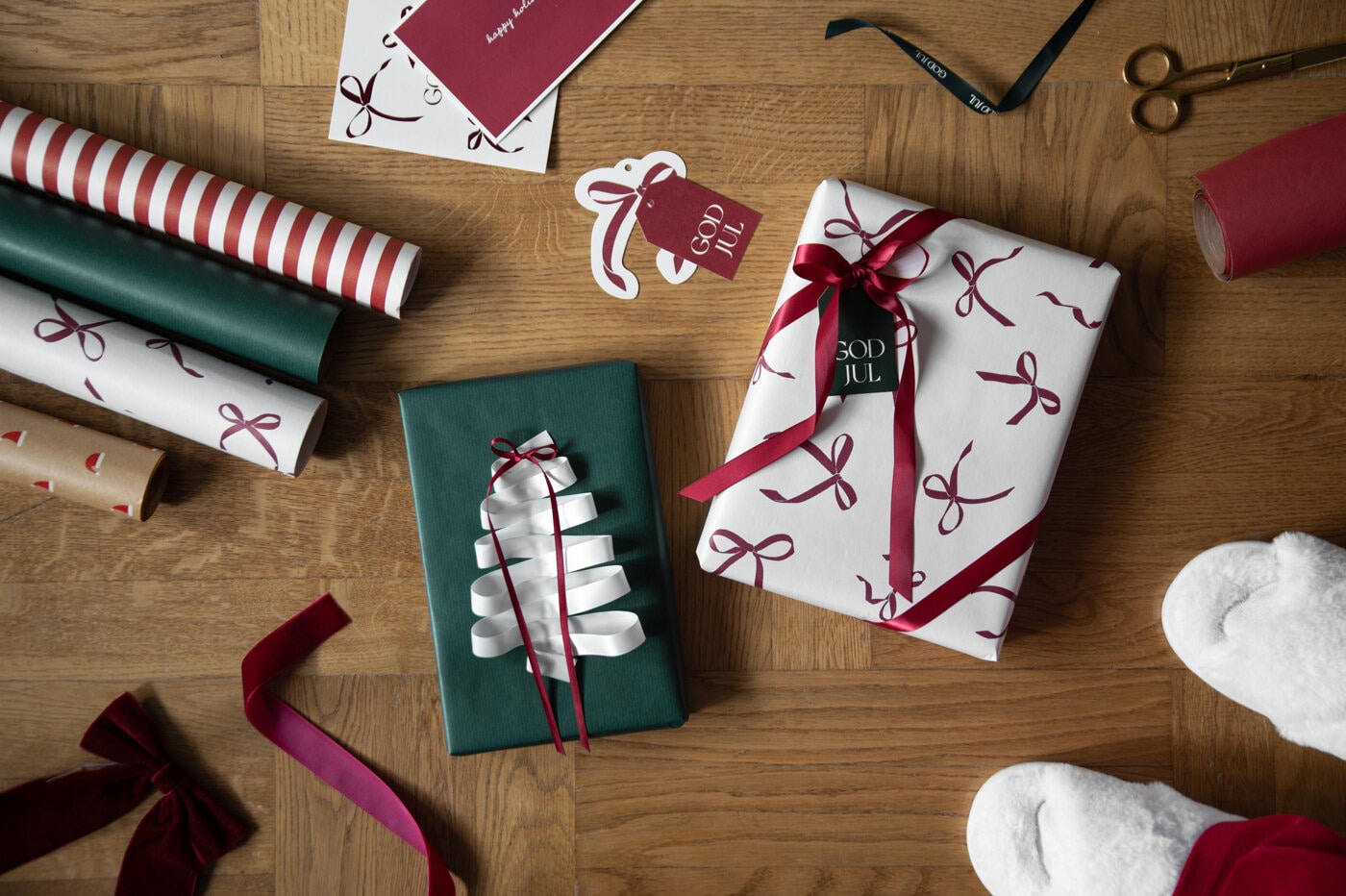 Inslagna julklappar i grönt och vitt med röda band och rosetter.