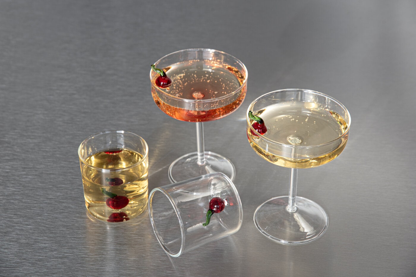 Glas och champagneglas Cherry med dekorativa körsbär, fyllda med dryck.