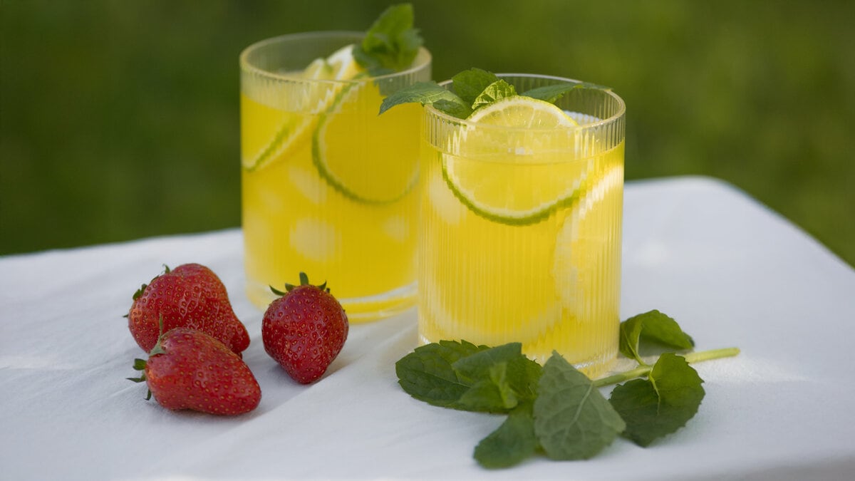 Ribbade glas med gul dryck och jordgubbar.