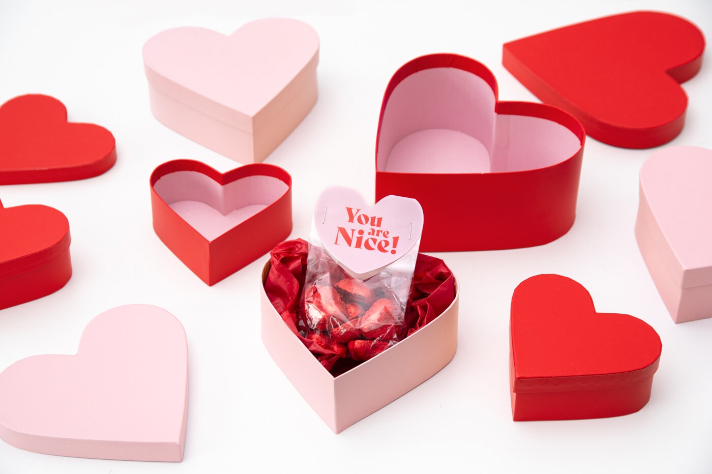 Hjärtformade askar i rött och rosa mot ljus bakgrund.