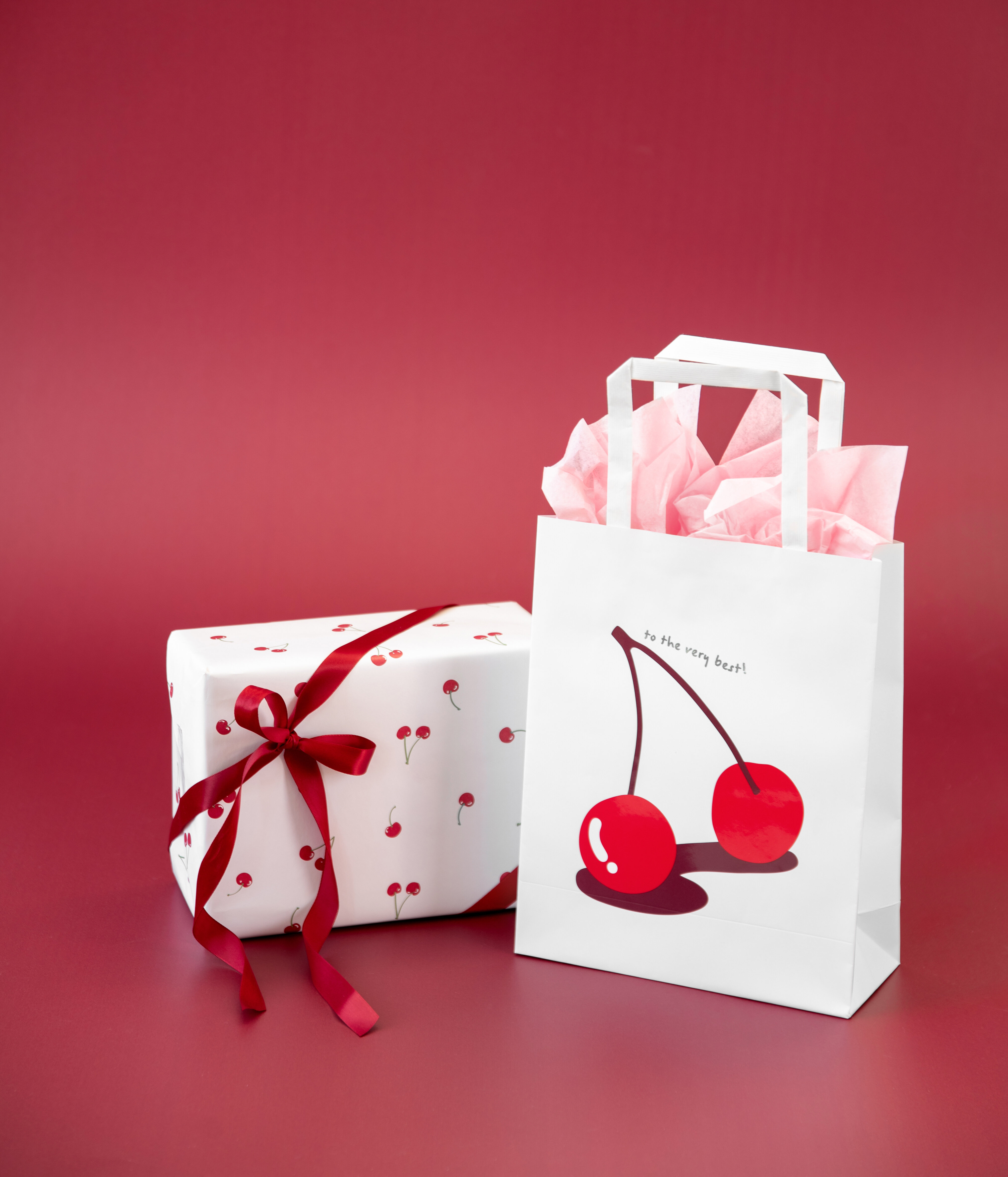 Presentpåse med körsbär oc inslaget paket med presentband,