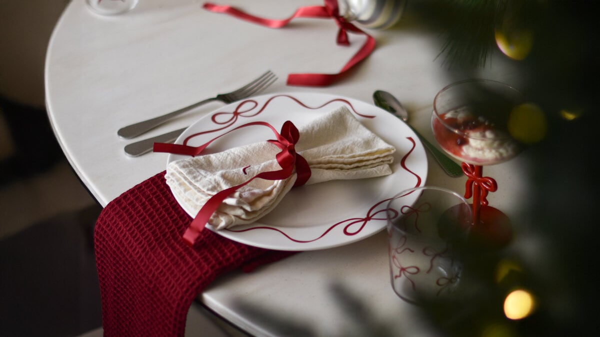 Juldukning med rosettmönstrad tallrik och rödknuten servett.