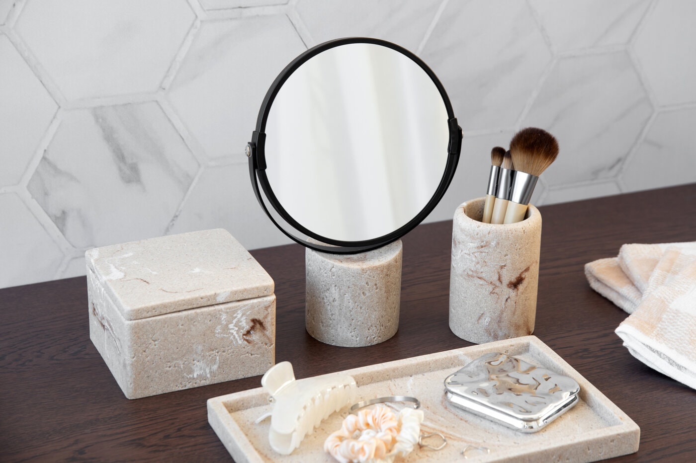 Badrumsaccessoarer i sten med spegel och sminkborstar.