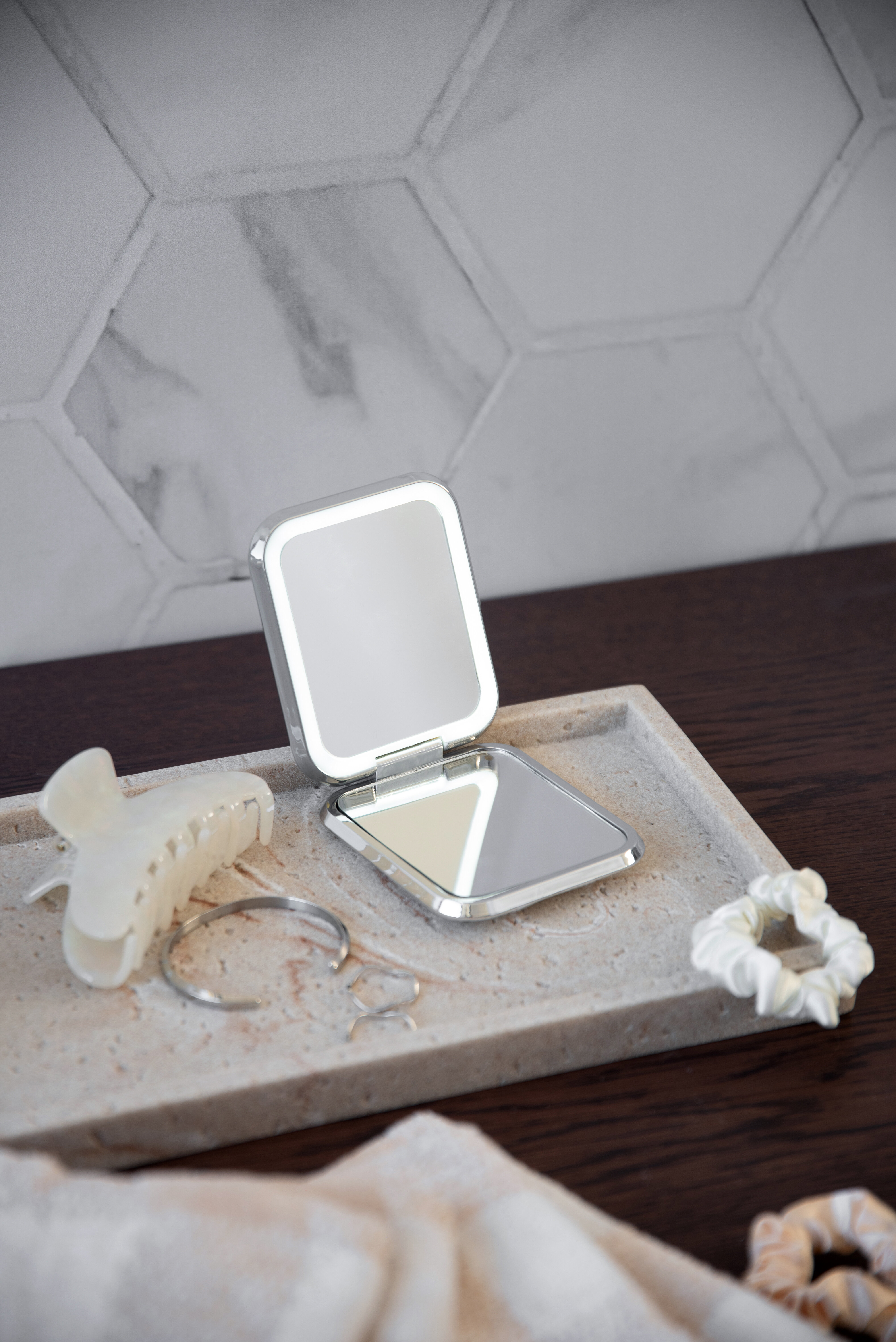 Liten spegel placerad på bricka med smycken och hårsnoddar