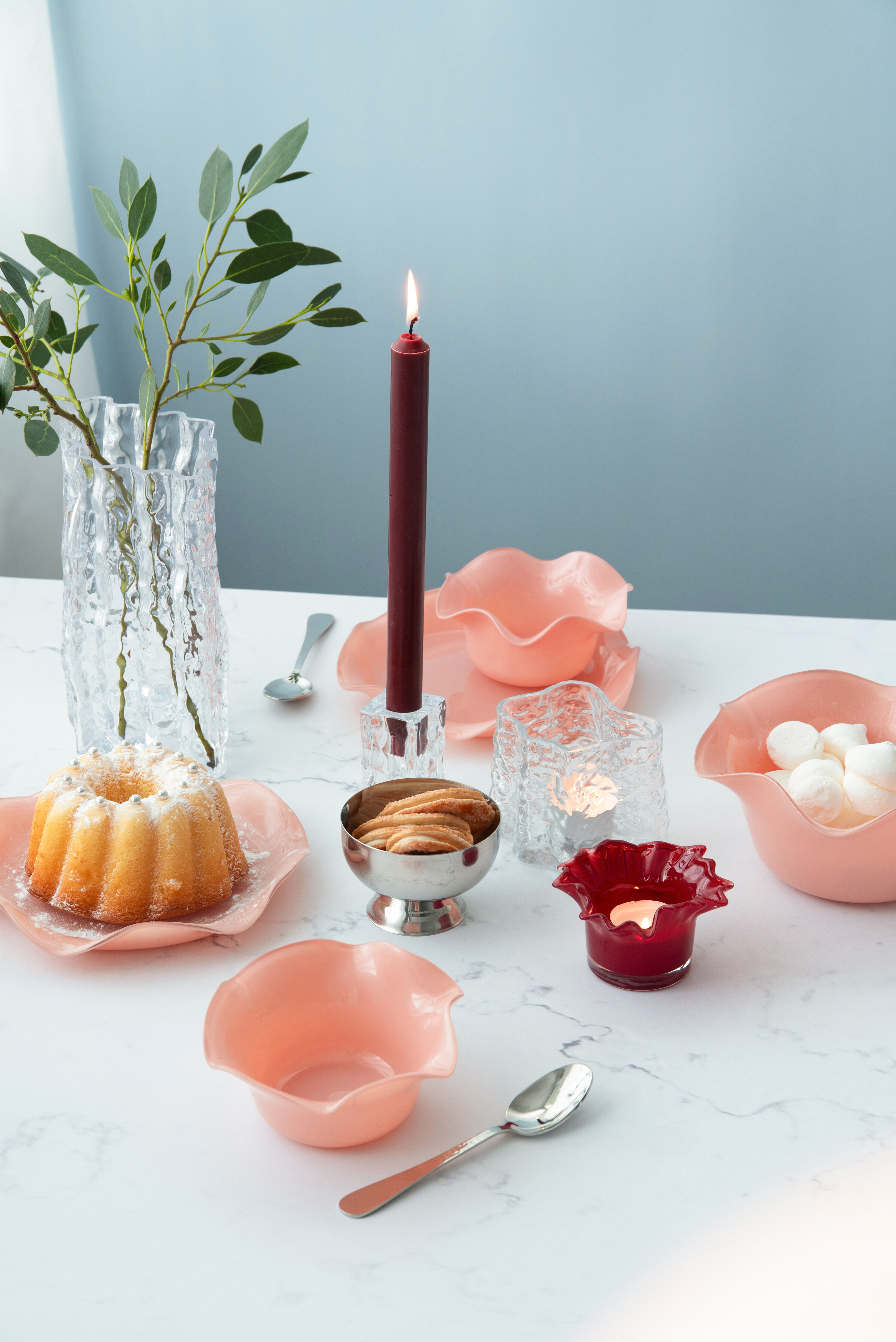 Dukat bord med färgat porslin, ljus och serveringsfat i glas och porslin.