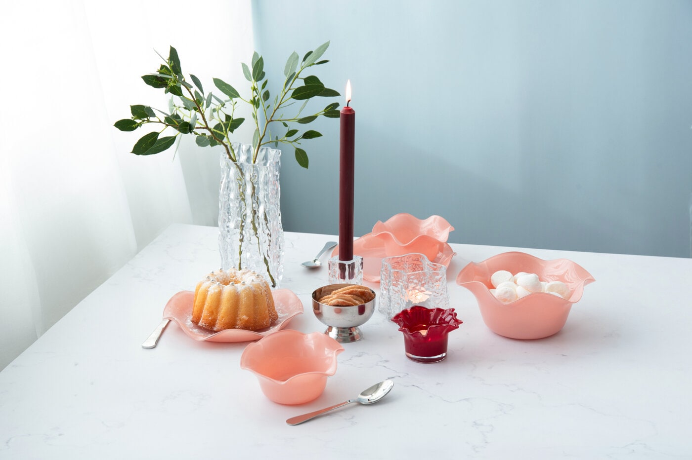 Dukning med ljus, kaka och serveringsskålar i rosa.