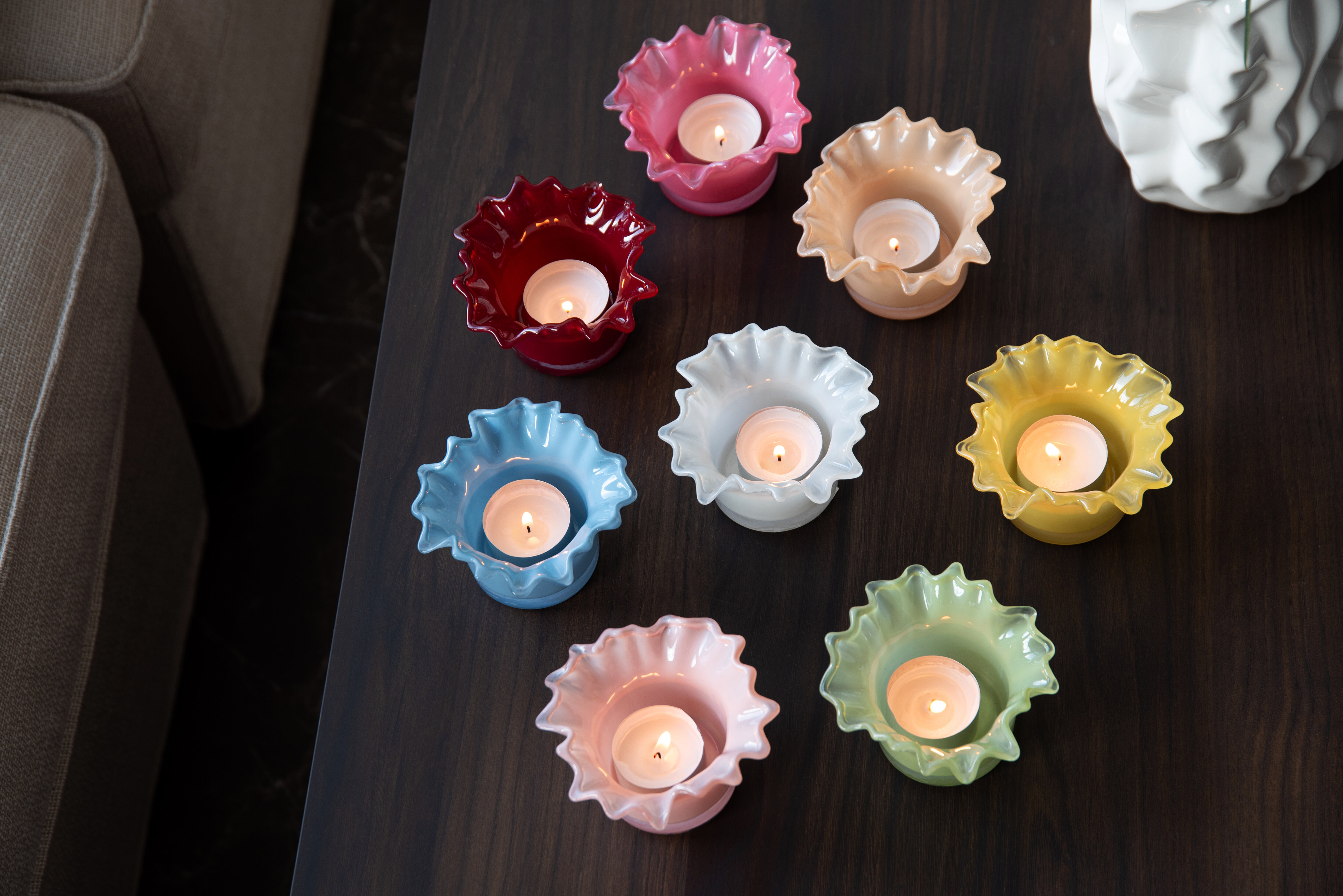 Färgglada ljuslyktor i glas med tända värmeljus, placerade på mörkt bord.