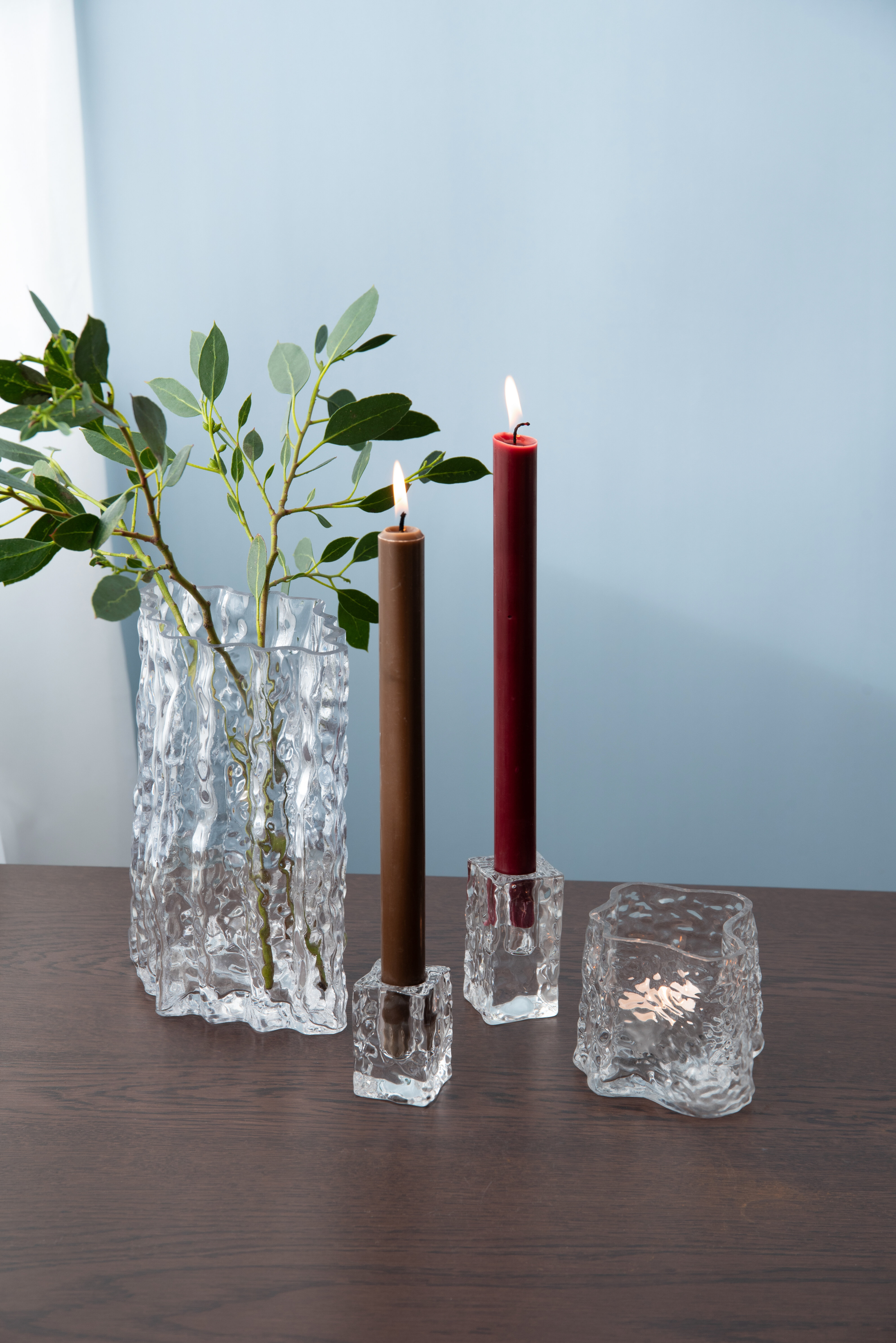 Inredningsdetaljer med ljusstakar, ljus och glasvas.