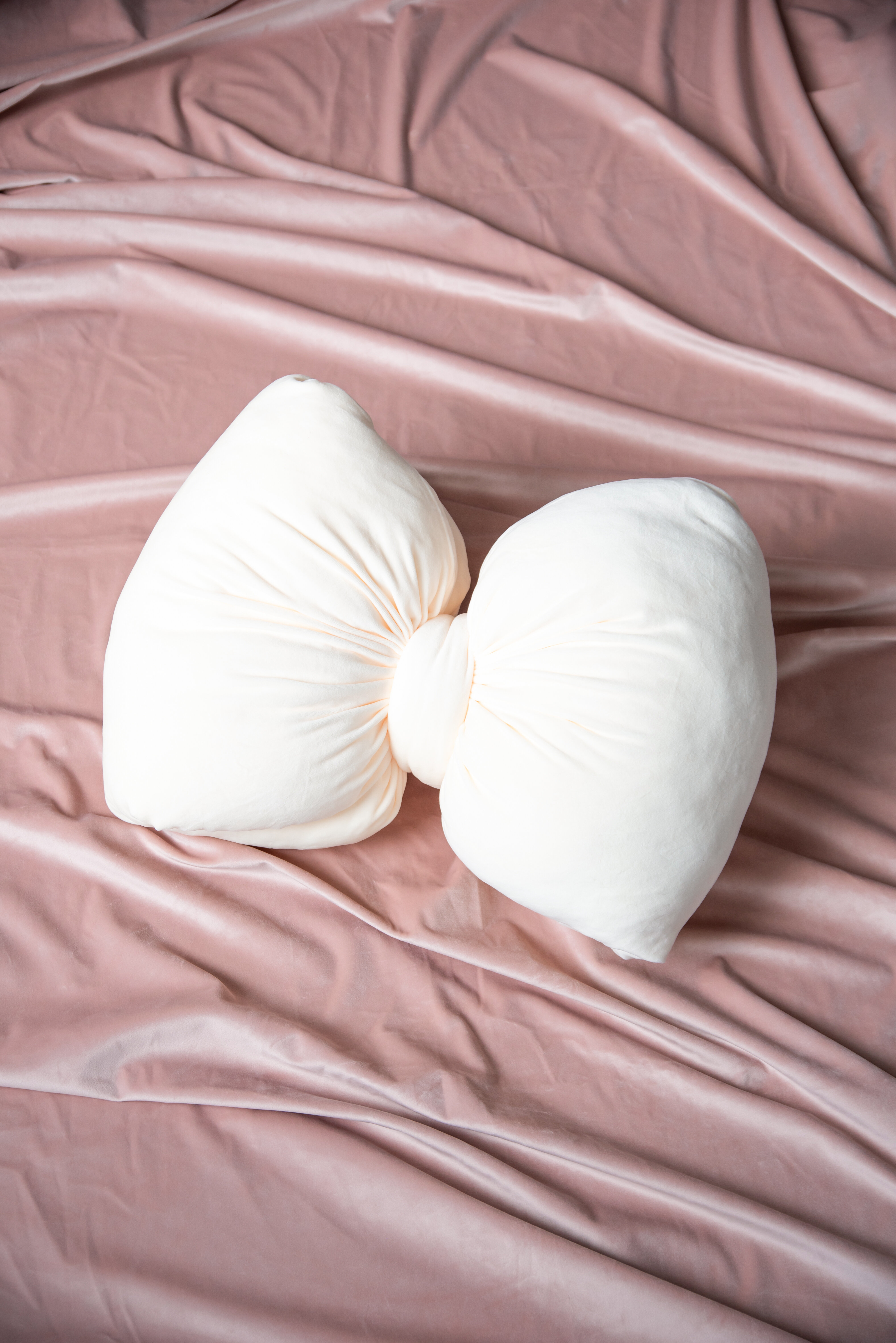 Vit rosettformad kudde mot rosa bakgrund