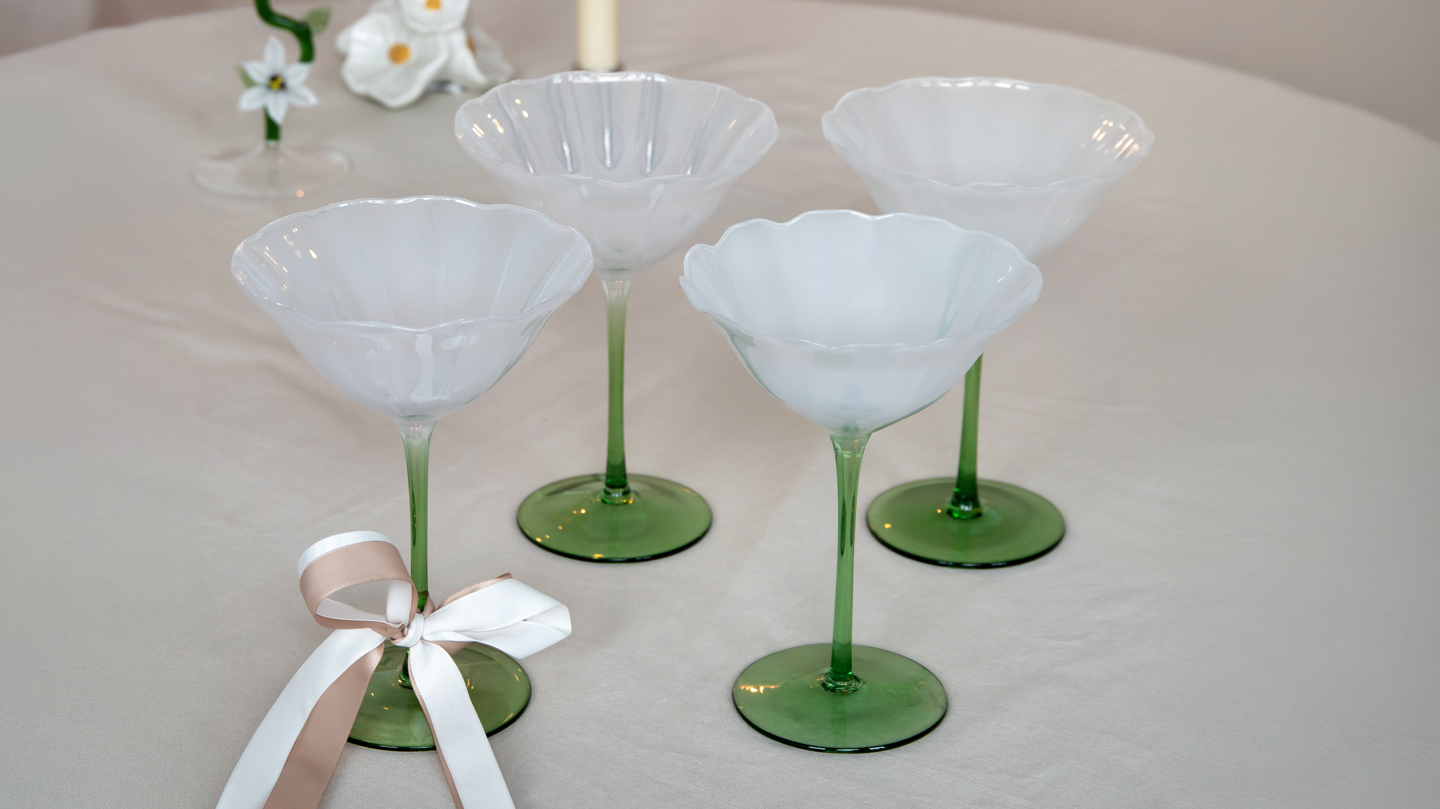 Fyra champagneglas placerade på ett dukat bord.