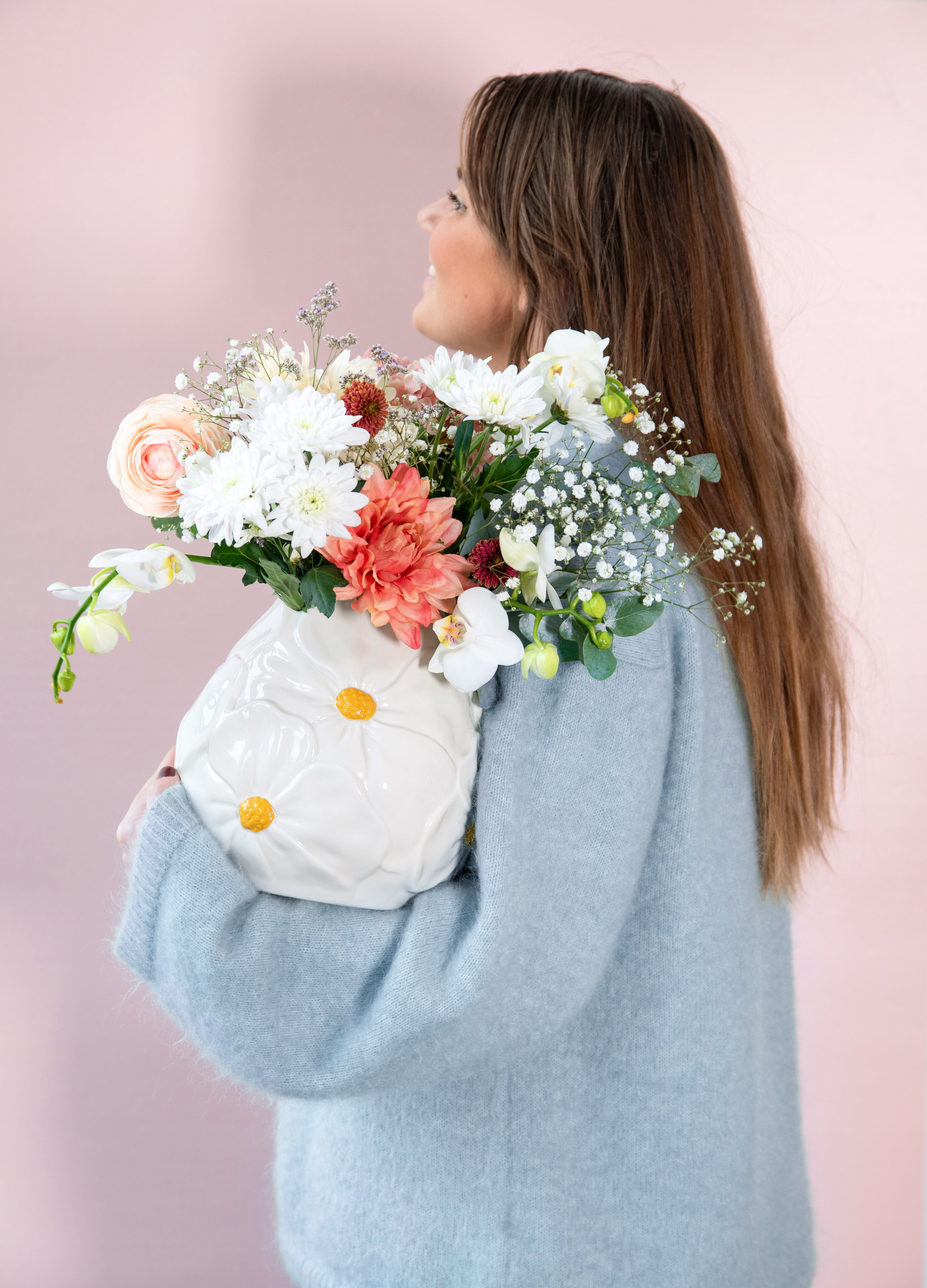 Person som håller i vas med blommor i.