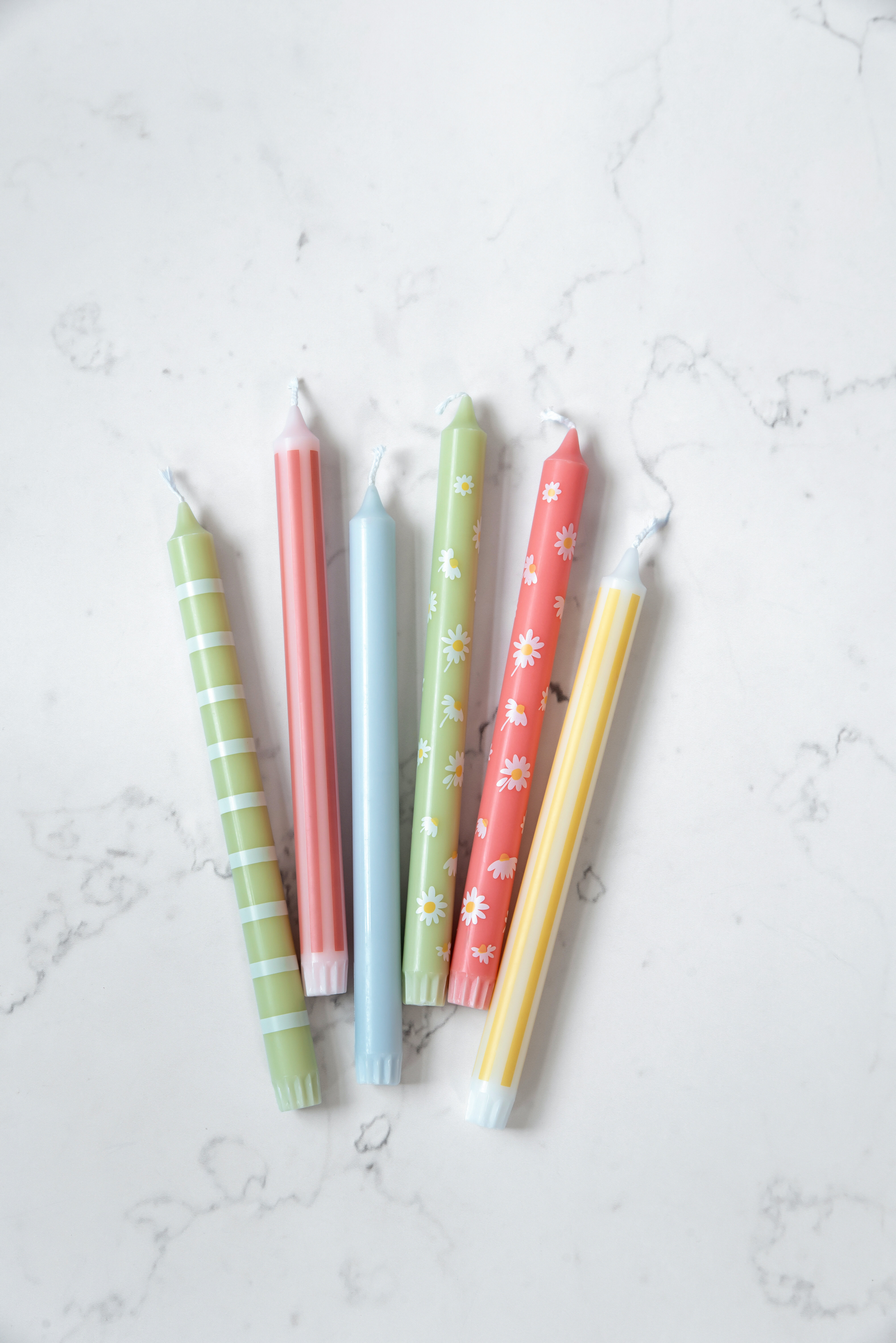 Rustikljus i olika färger mot marmorerad bakgrund.