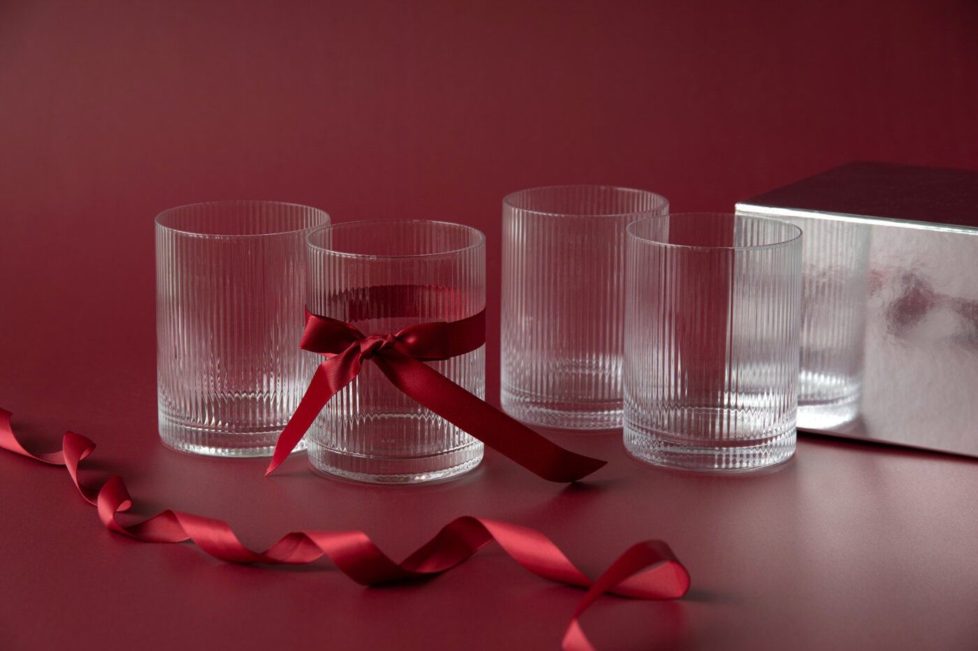 Räfflade glas i klarglas, ett dekorerat med en röd sidenrosett.