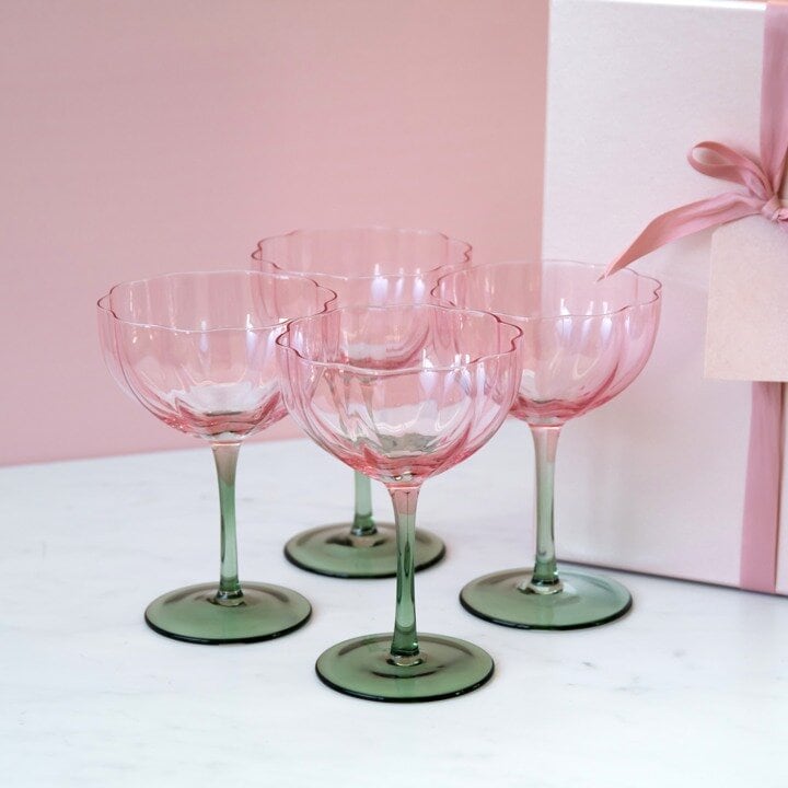Fyra blomformade coupeglas framför presentförpackning.