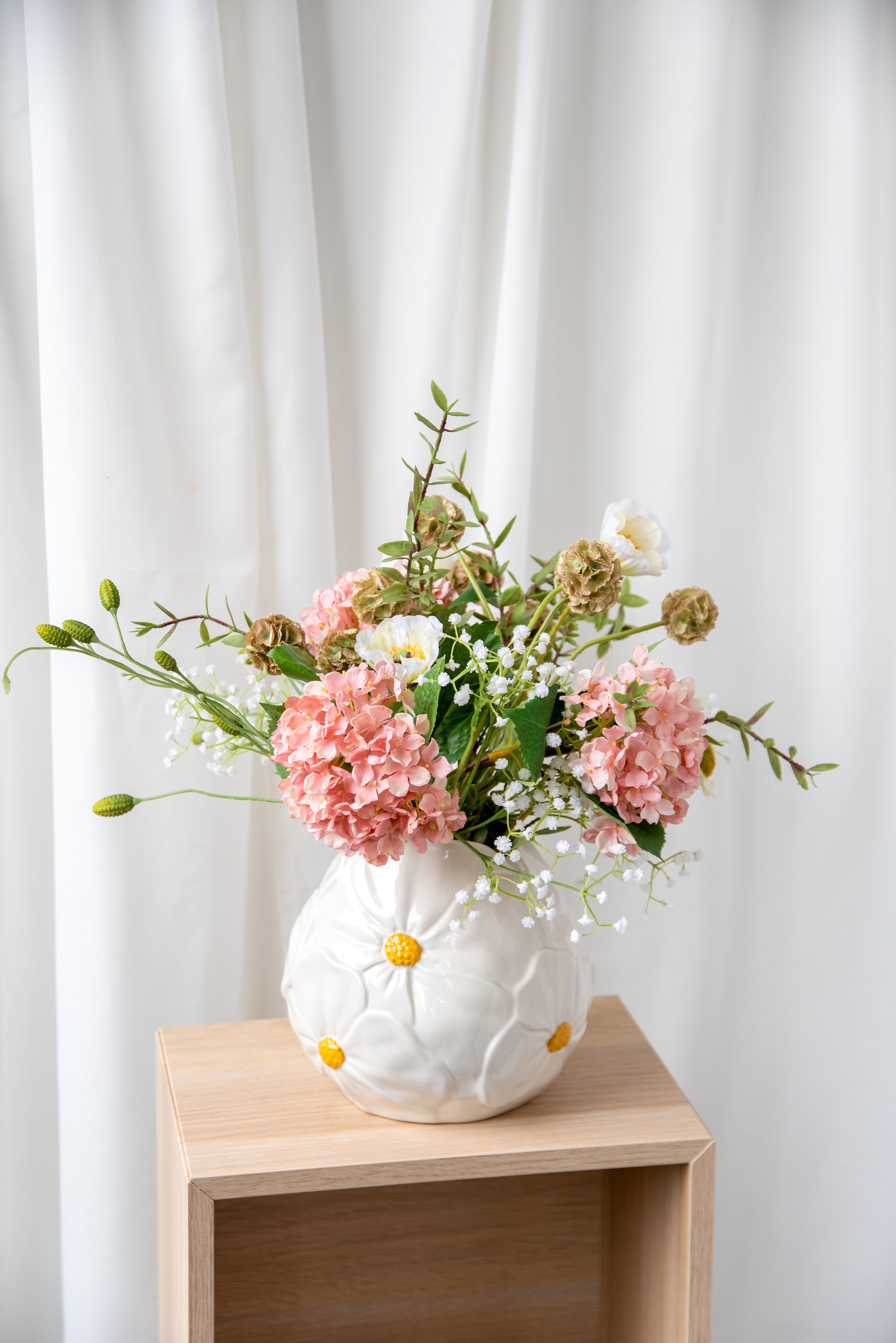 Vas med blommor i placerad på ett sidobord i trä.