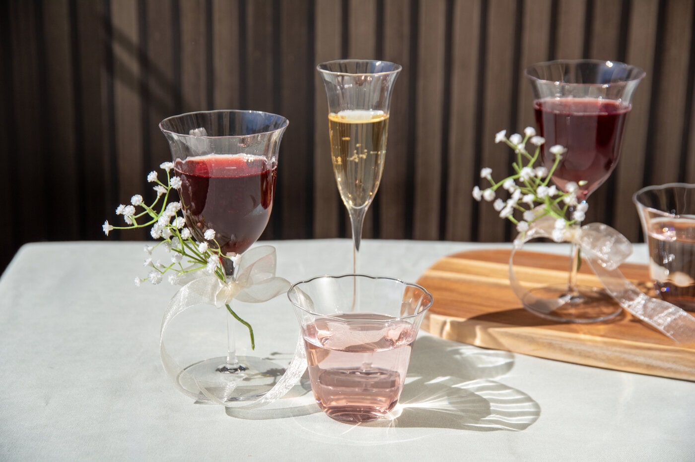 Serie med klockformade glas, vinglas, champagneglas och vattenglas med vita blommor.