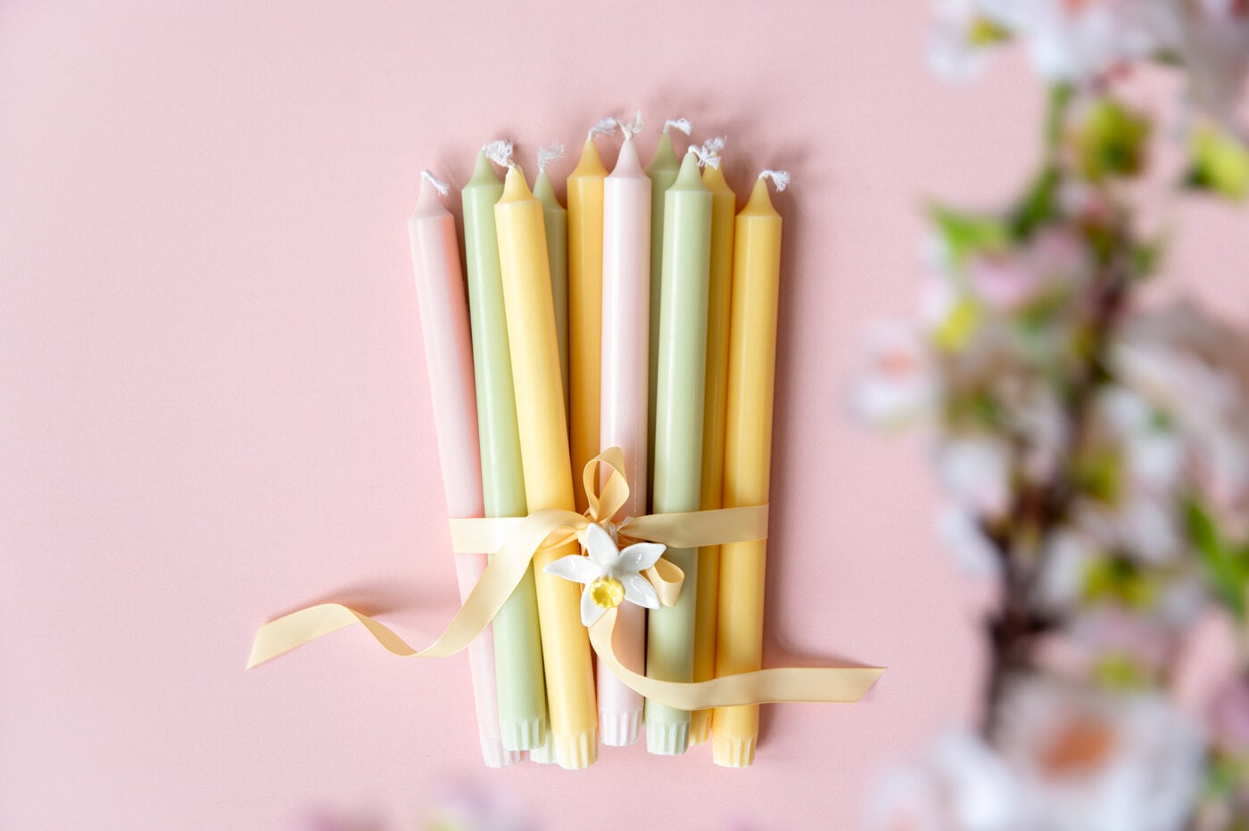 Bukett med rustikljus i vårfärger mot rosa bakgrund.