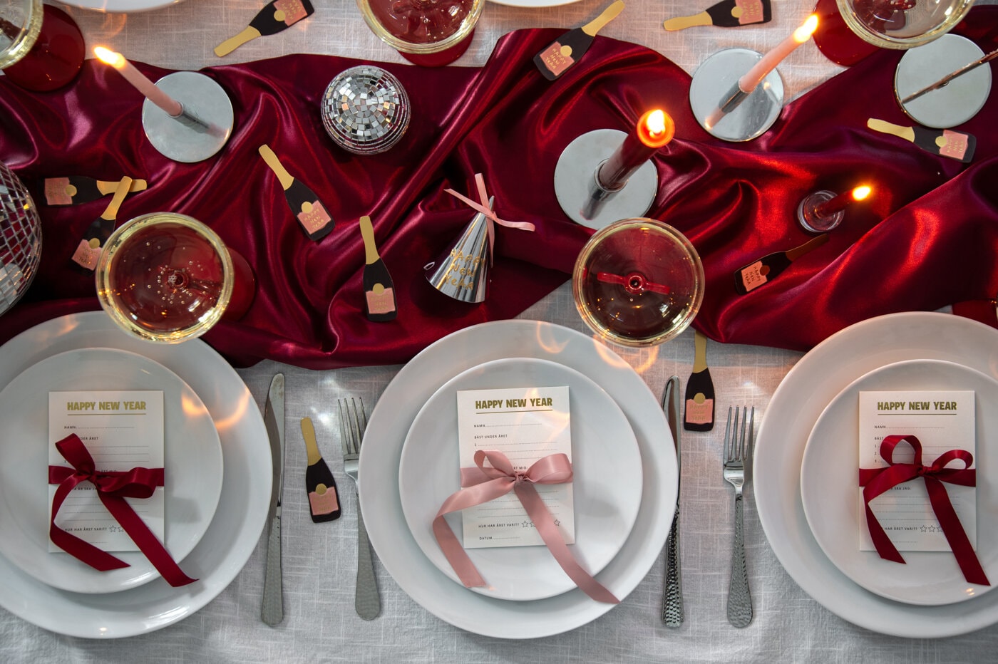 Nyårsdukning med röda detaljer, champagneglas och nyårsdekorationer.