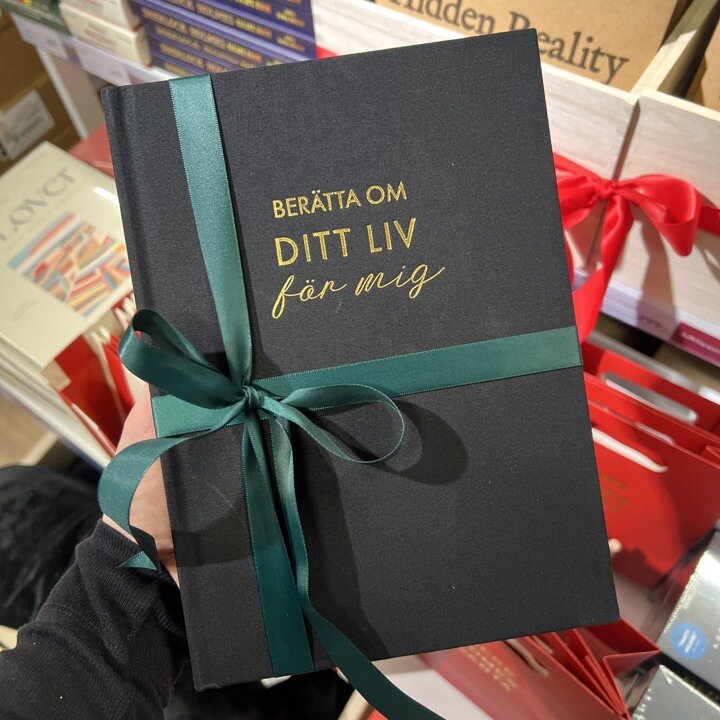 Presentbok med grönt satinband med rosett runt.