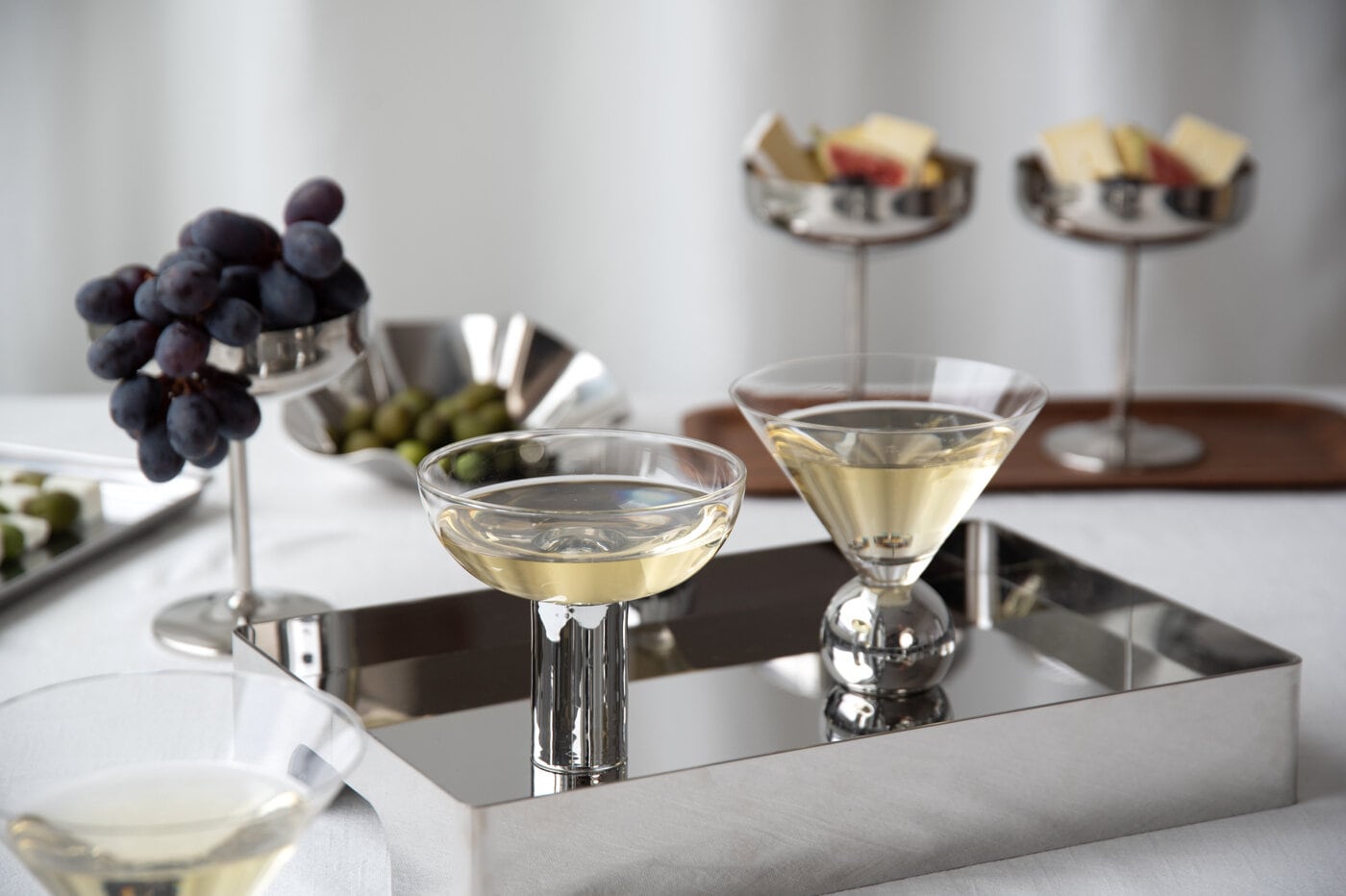 Drinkglas på silverbricka på ett dukat bord.