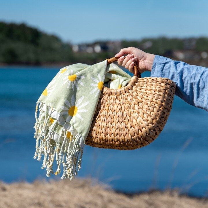 hand som håller i strandväska och handduk.