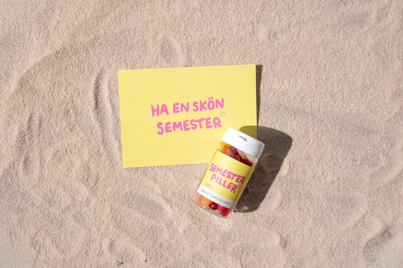 Vykort Gult vykort och godisburk med text på sandstrand