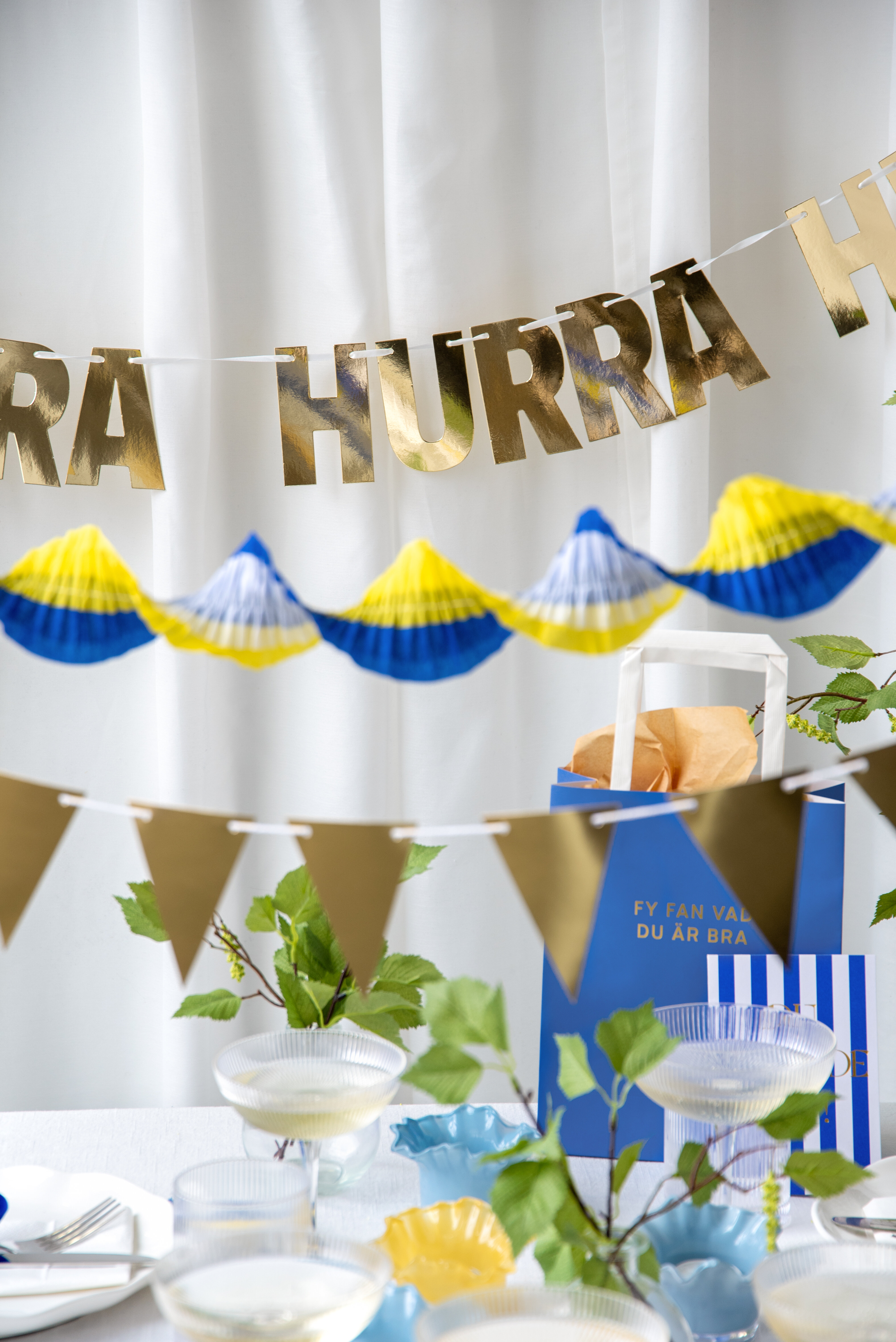 Blå‑gula vimplar och pappersgirlander för studentfirande.