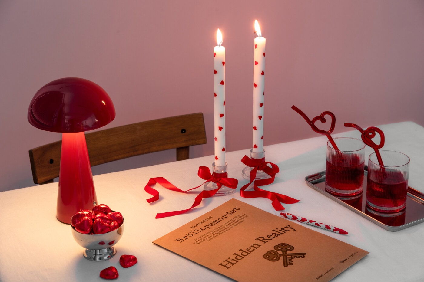 Romantiskt dukat bord med vita ljus dekorerade med röda hjärtan och röda band.