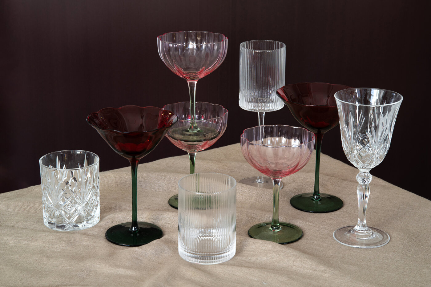 Olika glas samlade på ett bord med beige duk.