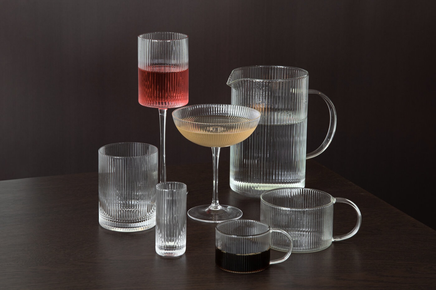Ribbade glas, karaff och coupeglas med dryck i.