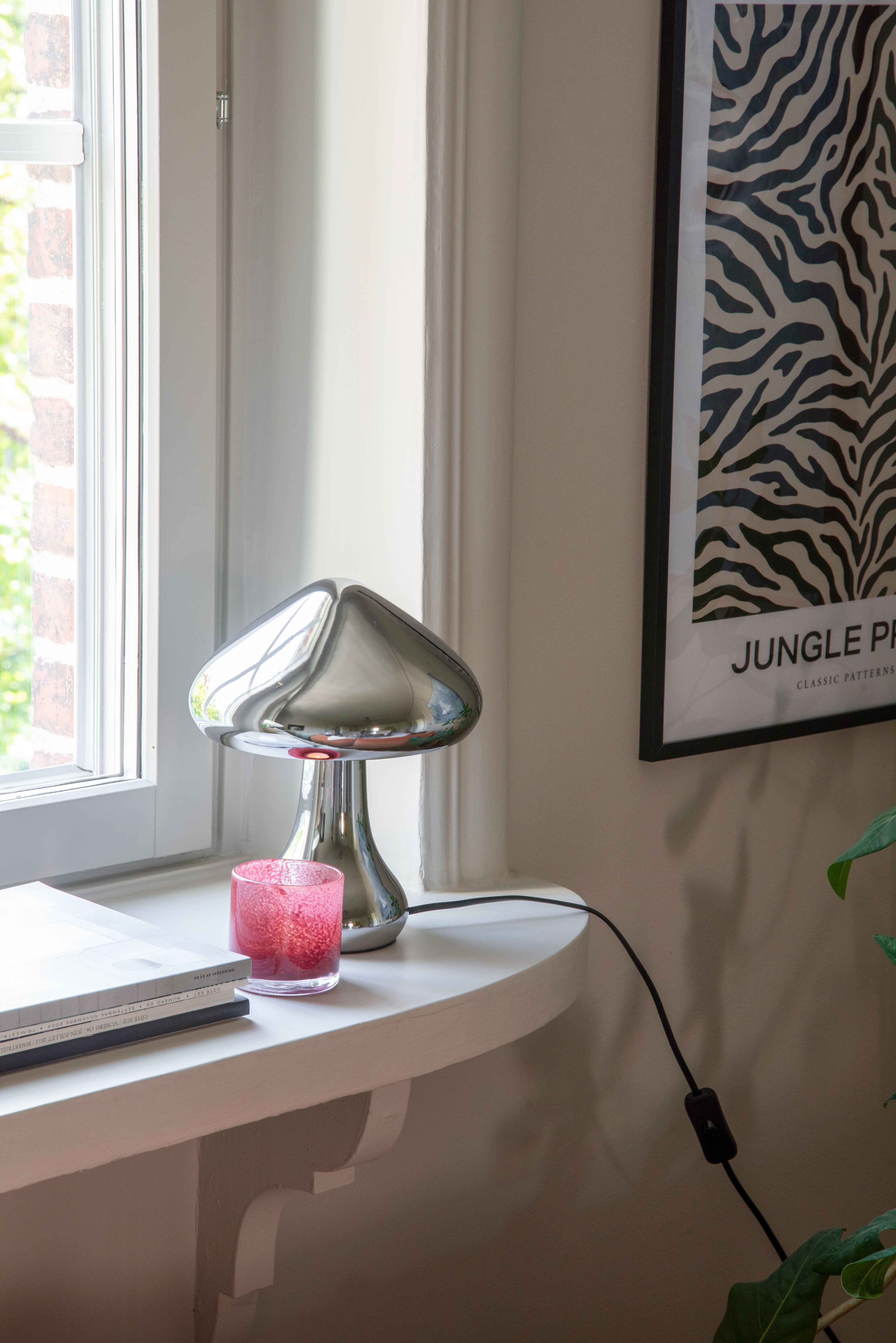 Silverfärgad bordslampa i fönsterbräda.